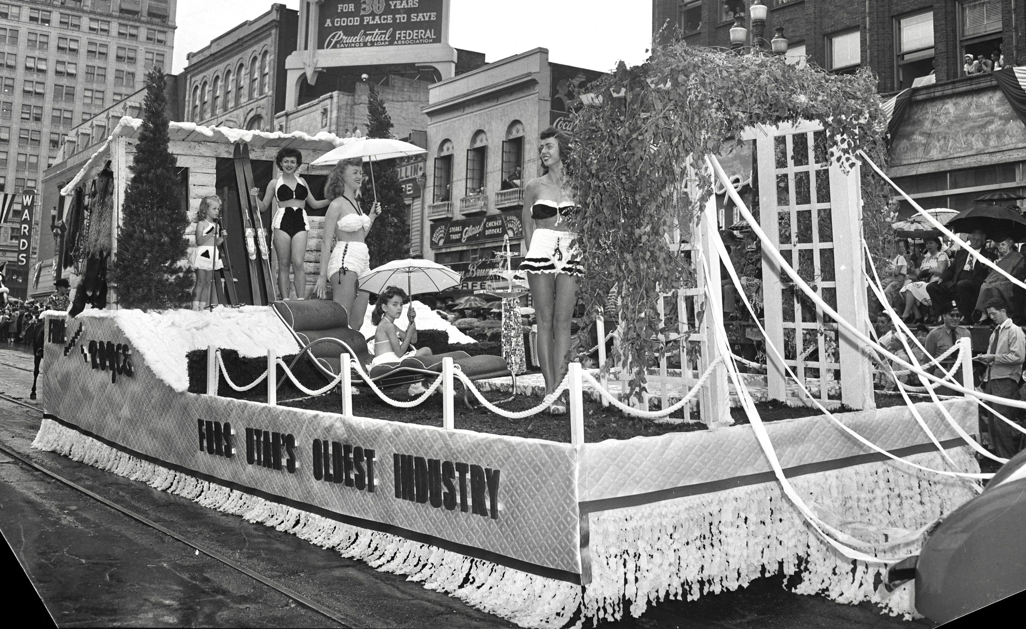 A 1946 parade float shows women in bikinis with a ski lodge and a pergola.