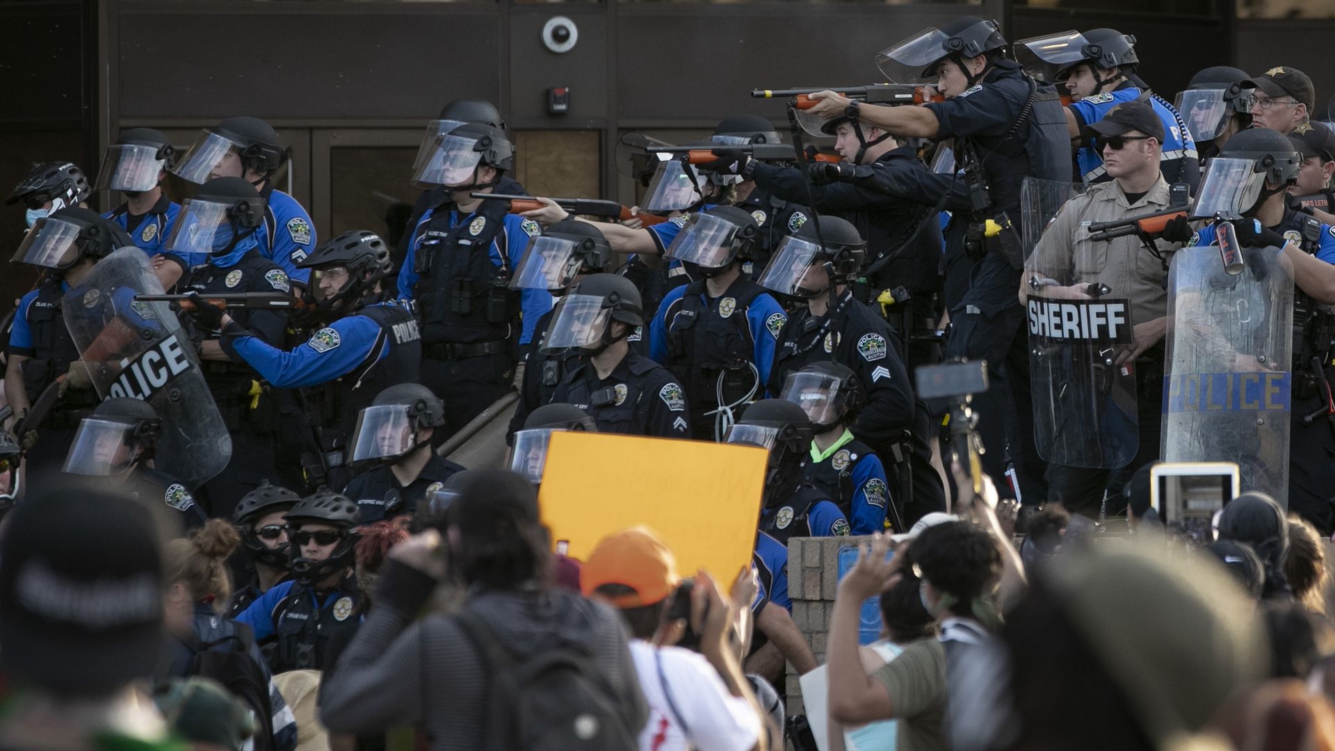 Police point weapons at protestors.