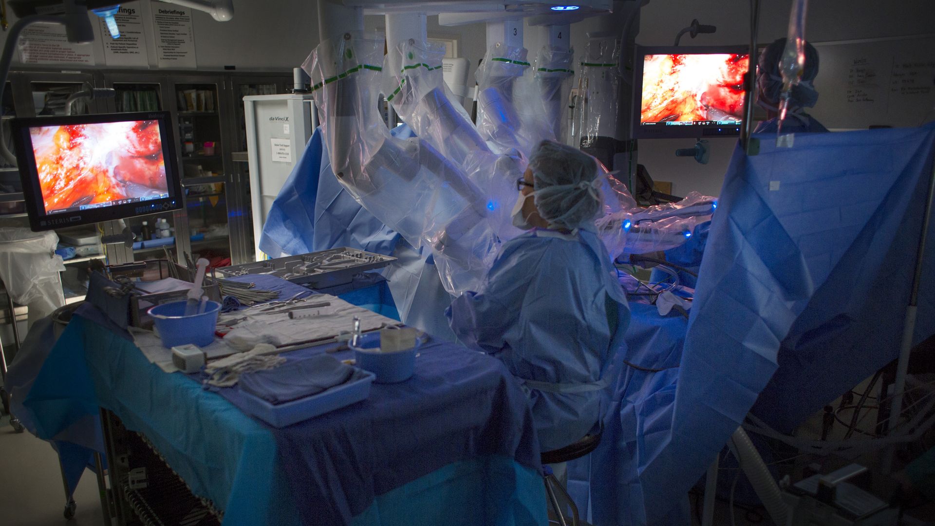 A nurses uses a surgical robot in a hospital operating room.