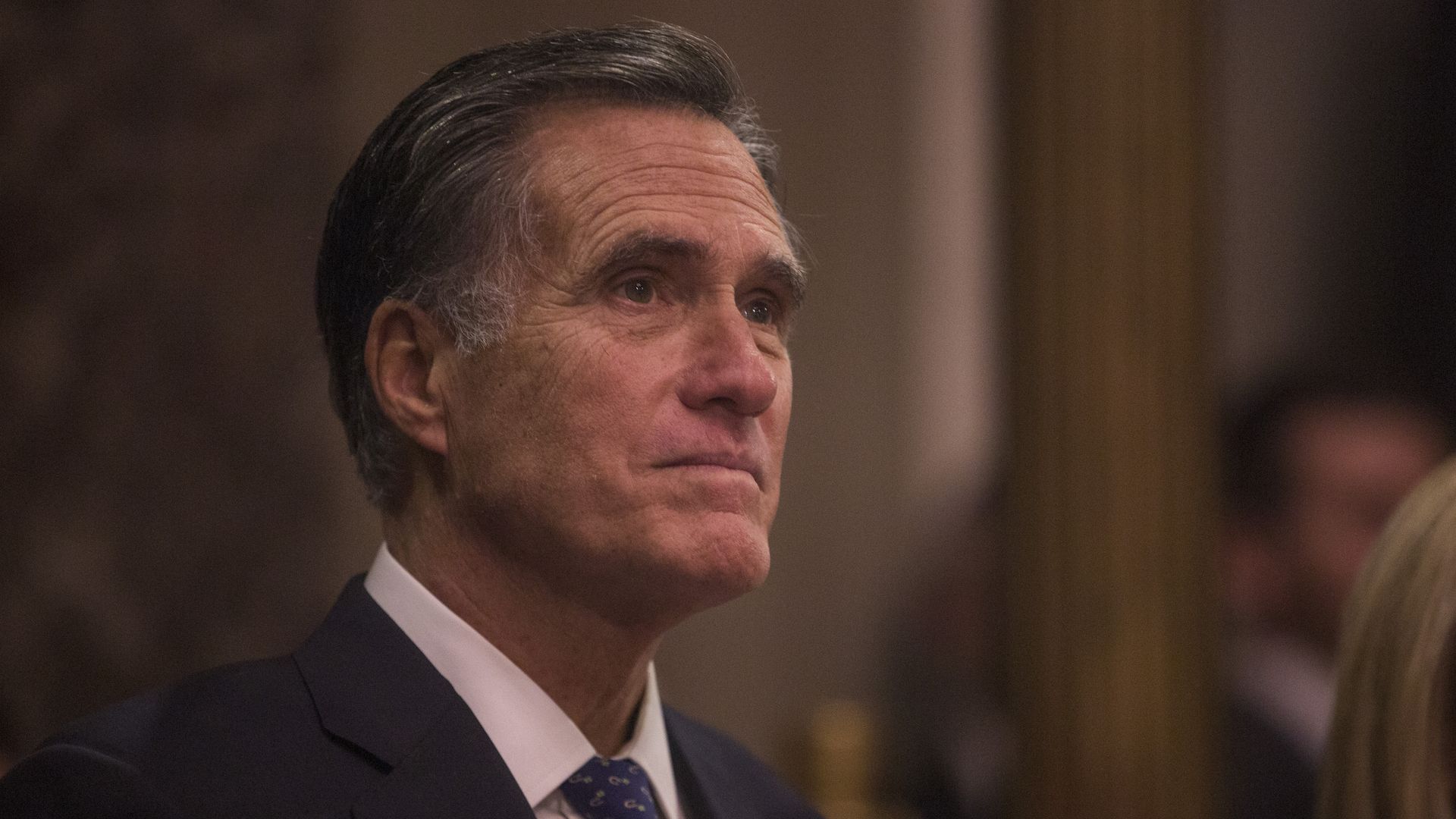 Mitt Romney is pictured standing in a suit at a swearing-in ceremony.
