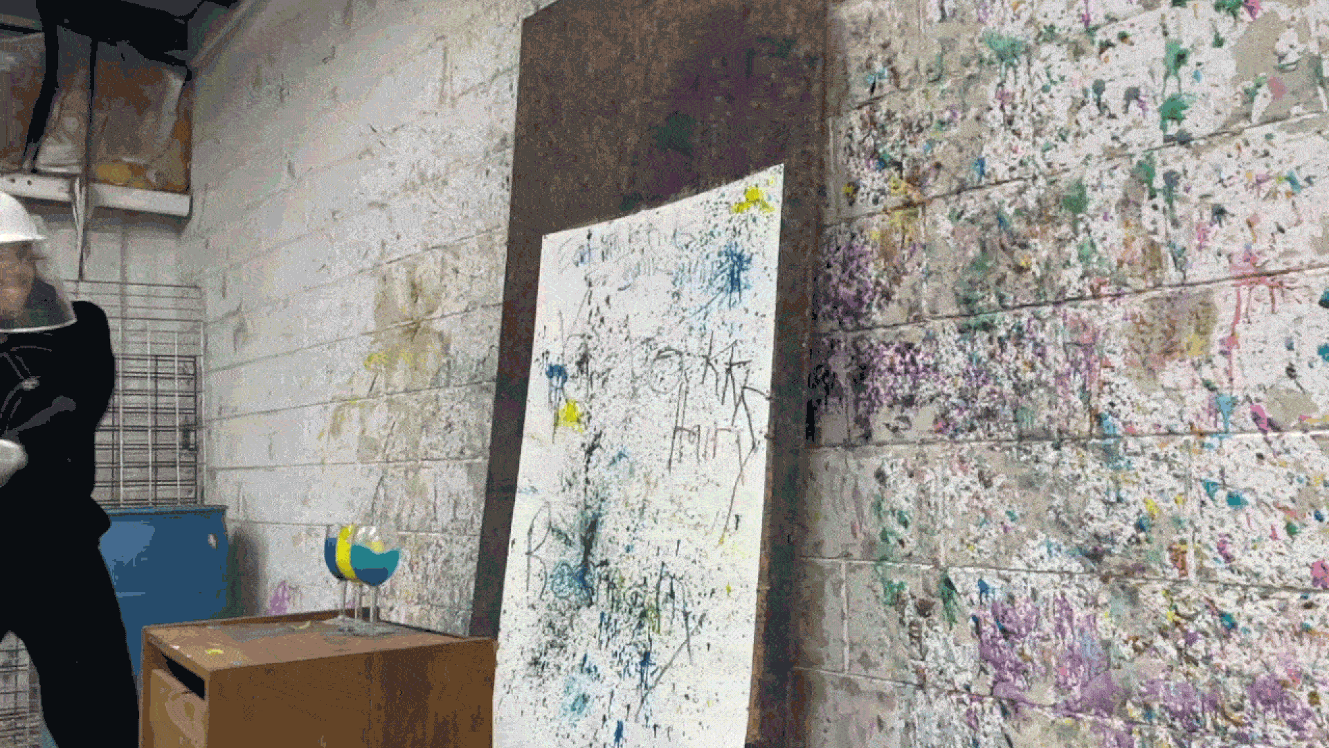 Selene using a baseball bat to smash wine glasses full of paint on a canvas