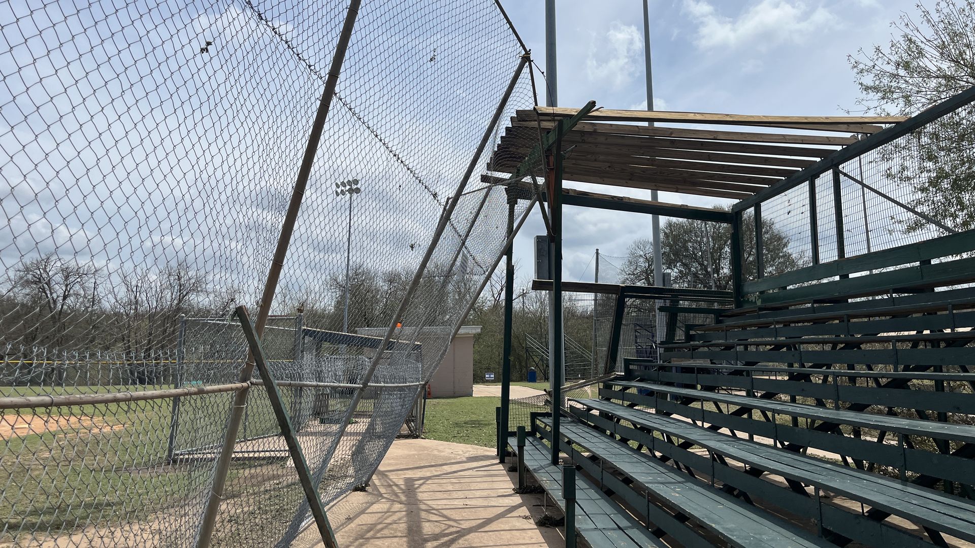 a photo of a bent in fence at a baseball field