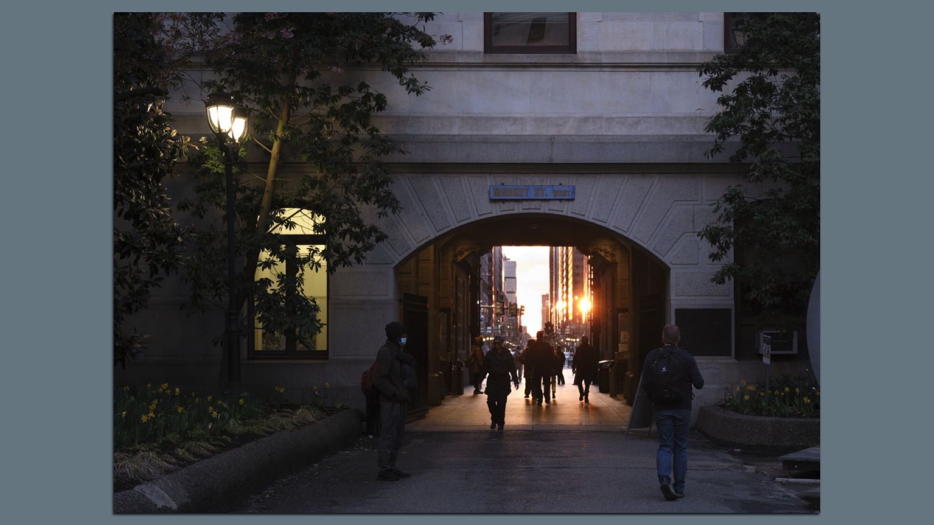 People walking through the "Market St West" at City Hall at sunset in Philly.