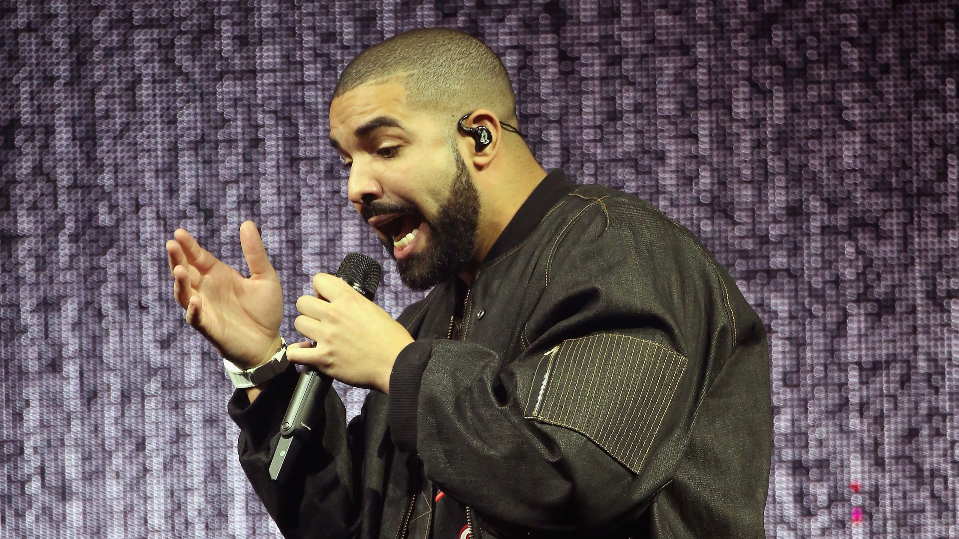 Drake raps into a mic in front of a blurred screen at the Wells Fargo Center in Philadelphia in 2016.