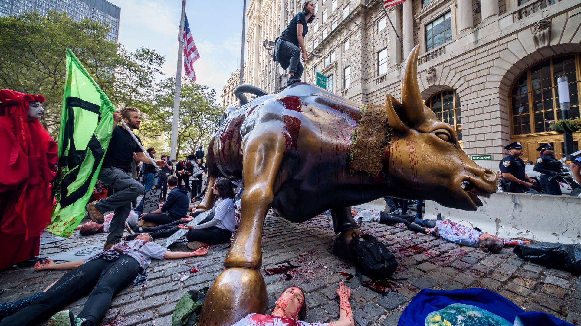 Climate advocacy group Extinction Rebellion stages protest on Wall Street standing on the bull statue and posing people with fake blood on the ground