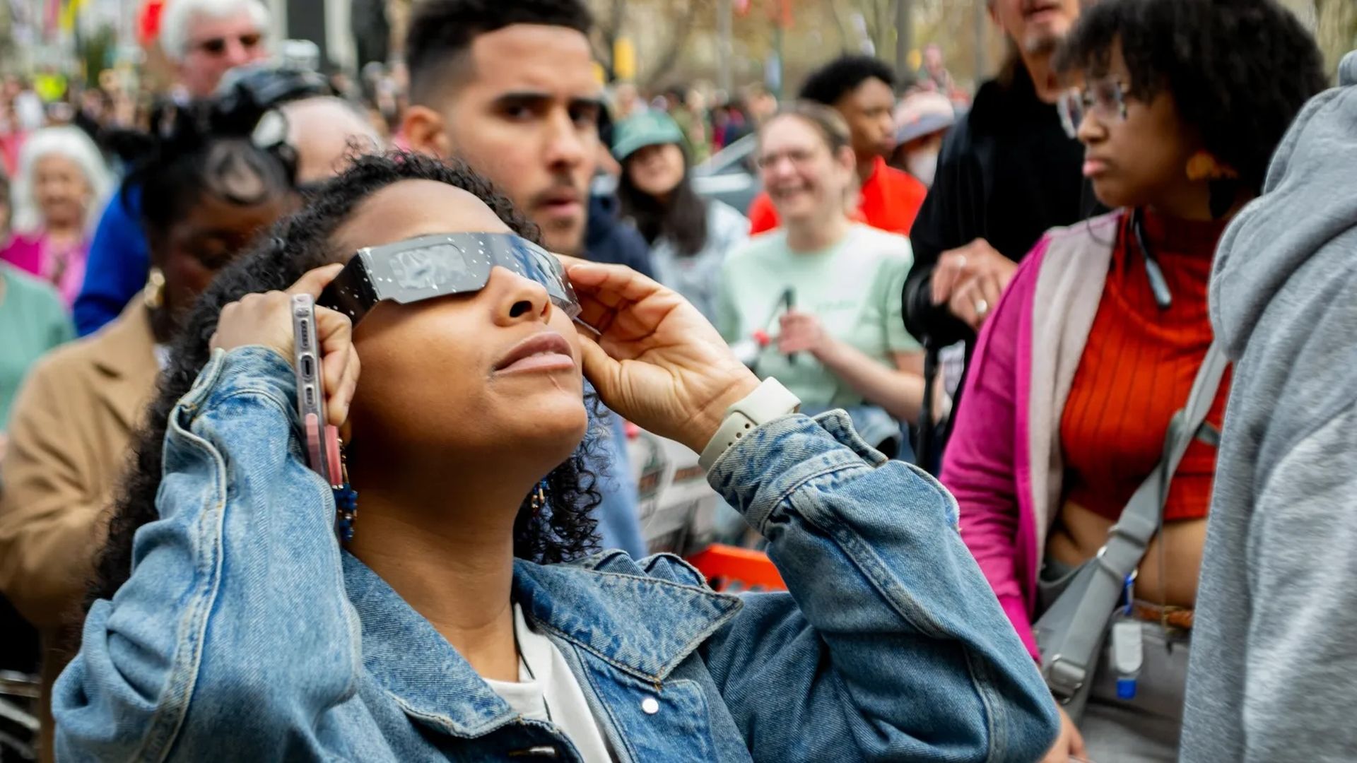 A woman looks up at the eclipse from the steps of the Franklin Institute