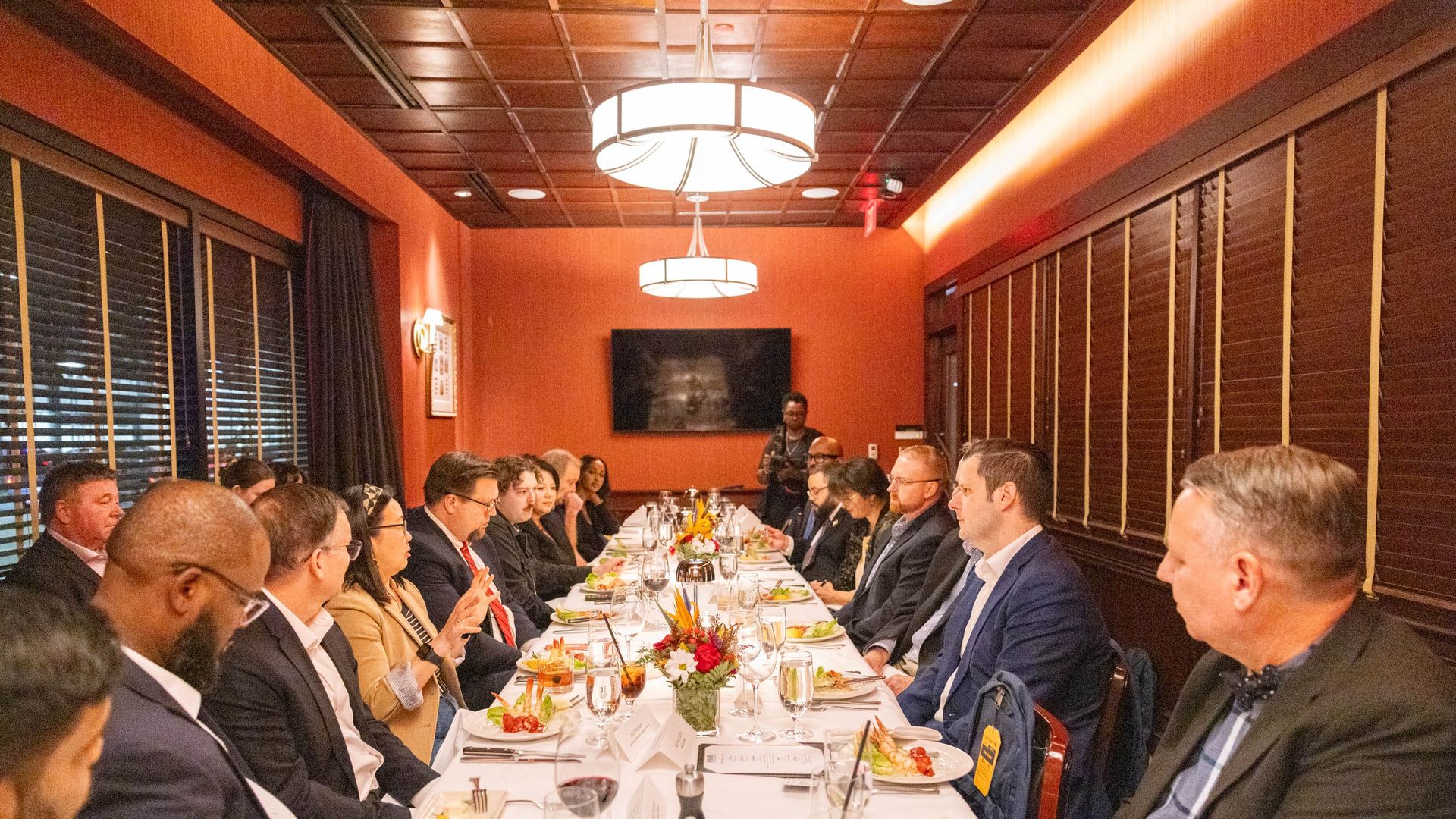 Attendees sitting around a rectangular table enjoying dinner during the discussion.