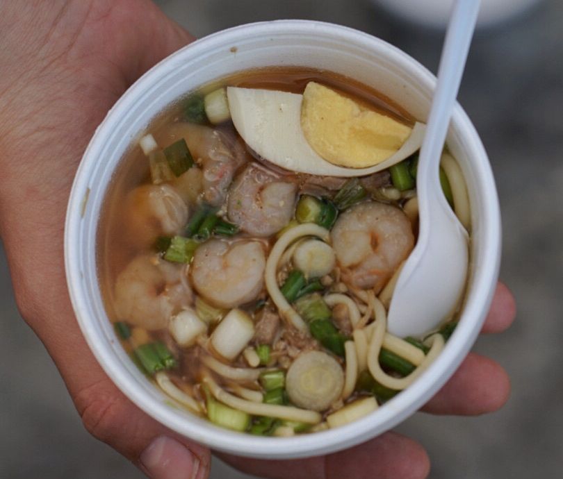Photo shows a cup of yakamein with shrimp, beef and a boiled egg.