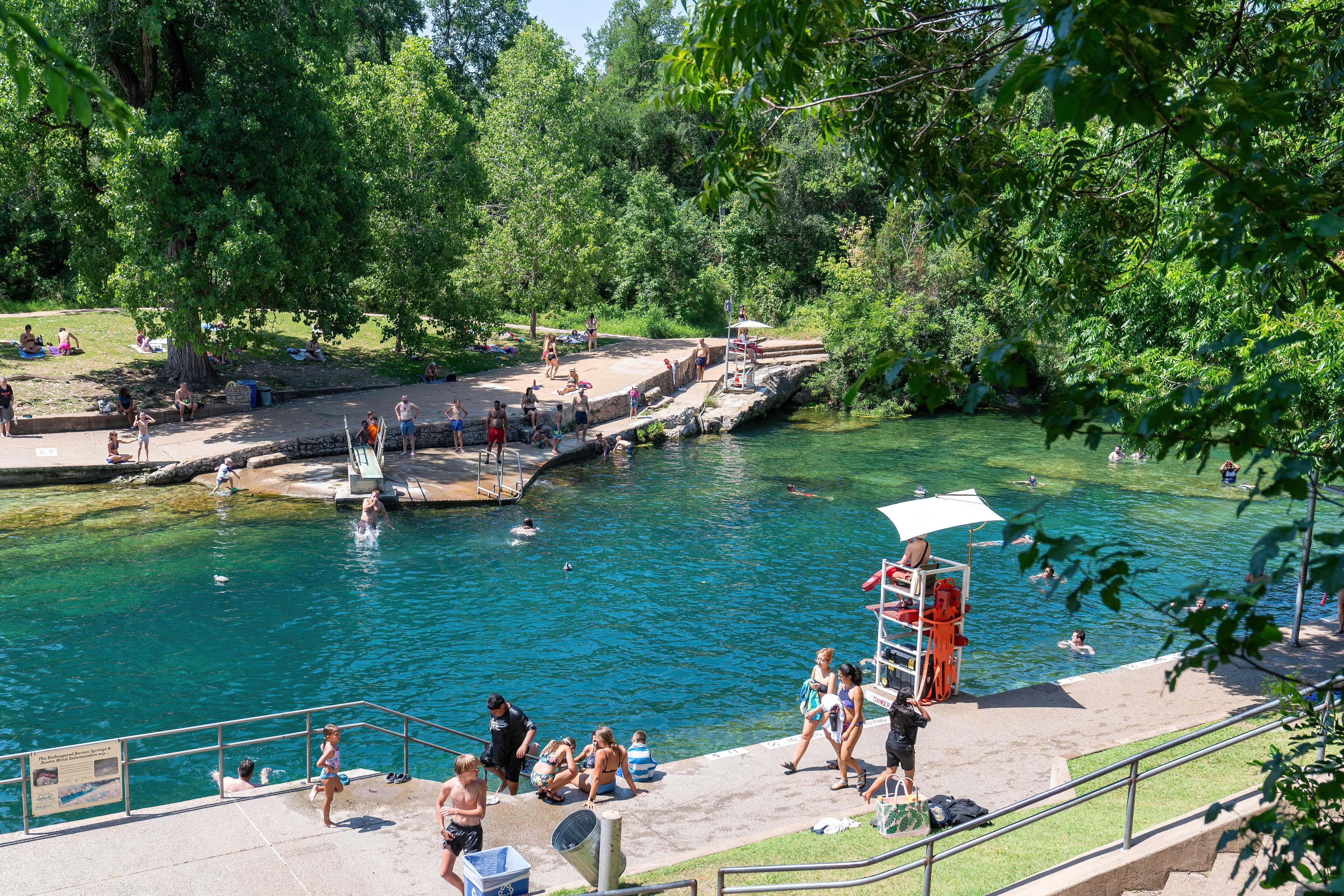 A photo of a pool with a lifeguard stand and swimmers on the edge.