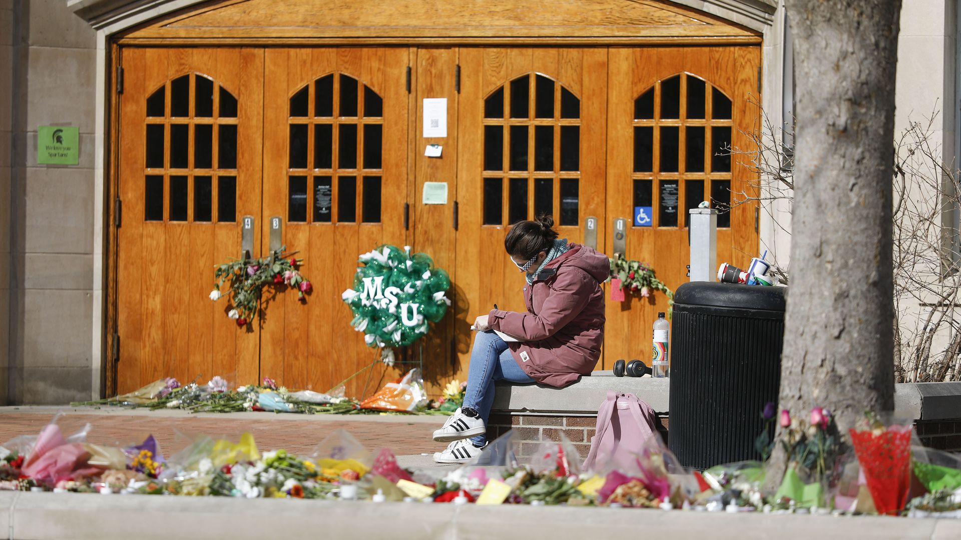 A person sitting outside Berkey Hall at Michigan State University, the site on a mass shooting on Feb. 13.