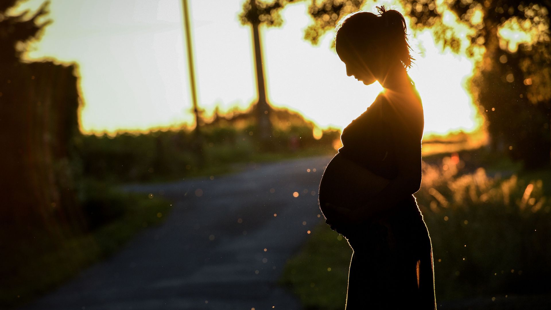The silhouette of a pregnant woman in front of a sunset