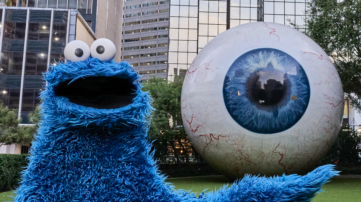 Cookie Monster stands next to a giant eyeball