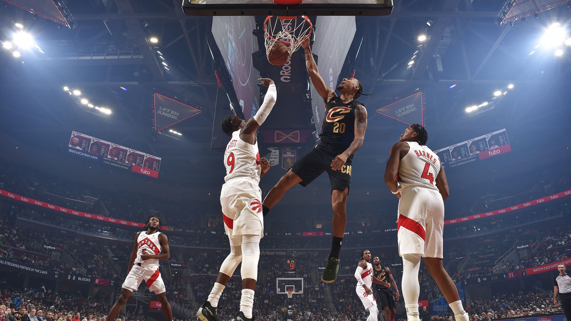 Pro basketball player in black jersey dunks ball amidst players in white uniform