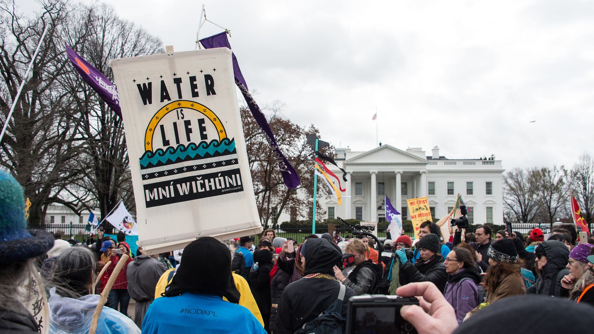In this image, protestors hold a banner that reads "water is life" in front of the White House.
