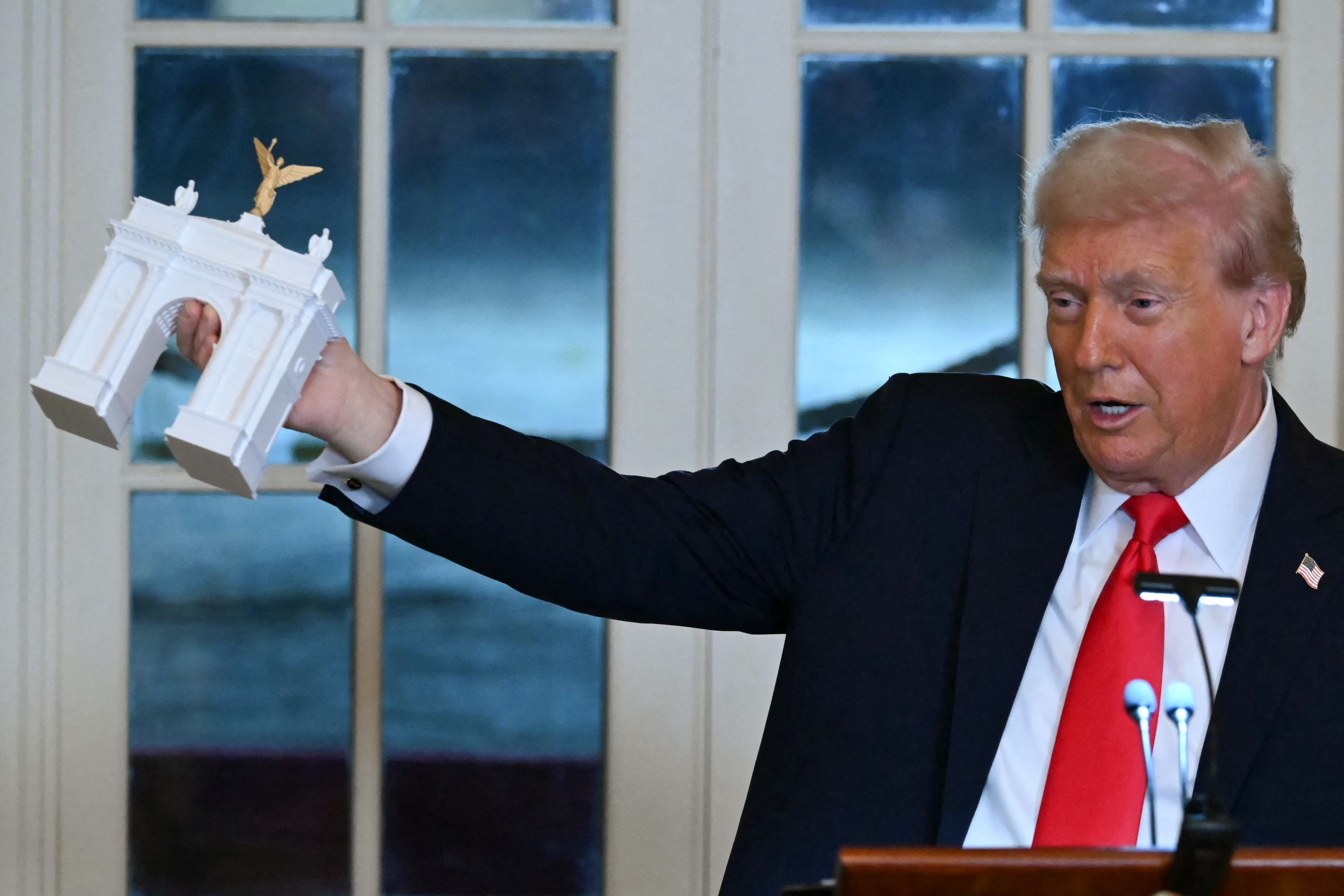 President Donald Trump holds up a model for a proposed "Independence Arch" as he speaks during a dinner with ballroom donors in the East Room of the White House in Washington, DC on October 15, 2025. US President Donald Trump, who is remodeling the White House to his tastes, will build a massive ba