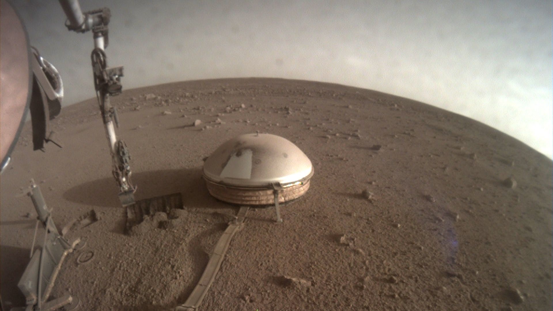 A view of InSight's instruments on Mars bathed in yellow/red light.