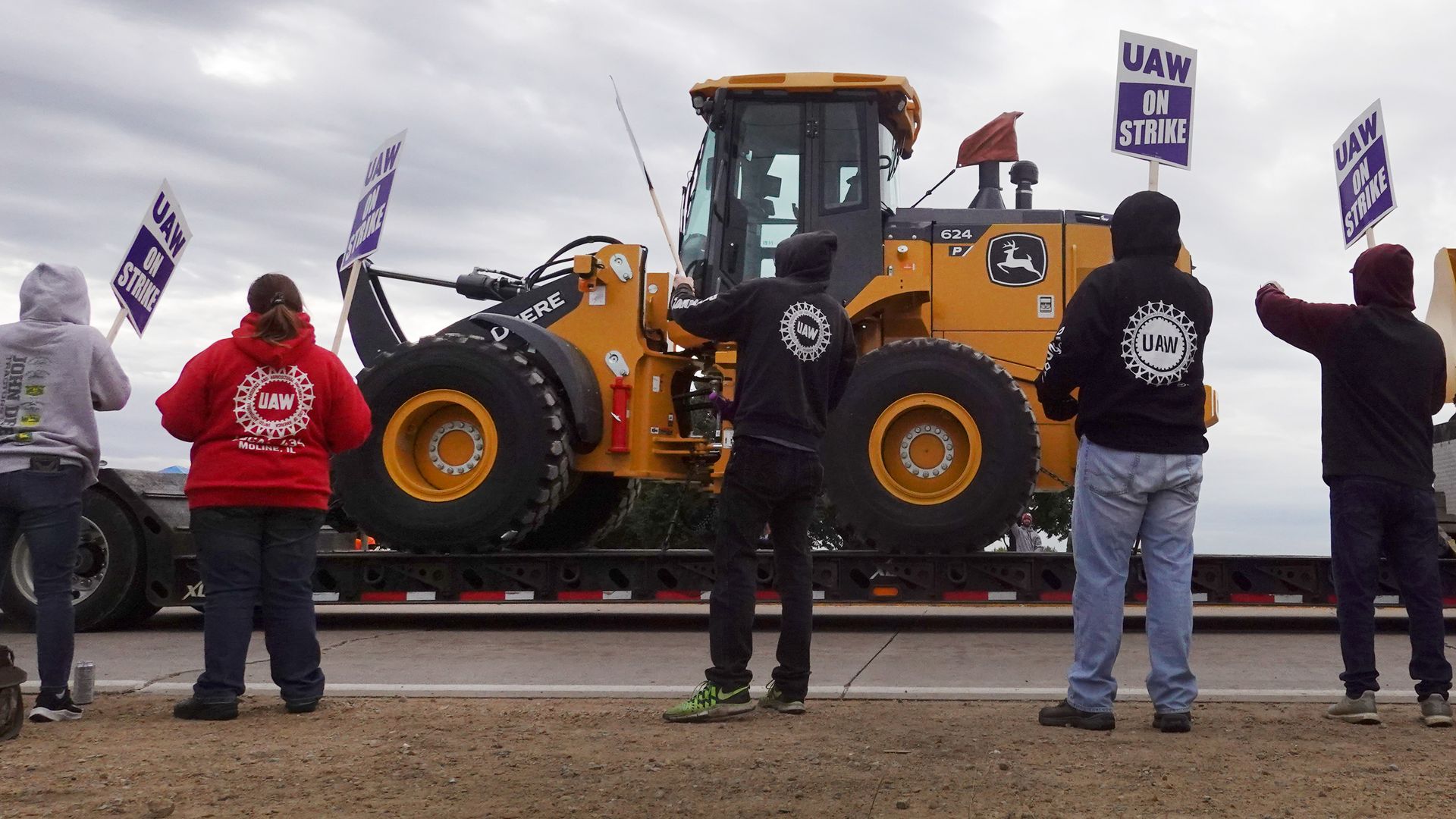 At truck hauls a piece of John Deere equipment from the factory past workers picketing outside of the John Deere Davenport Works facility on October 15, 2021 in Davenport, Iowa.