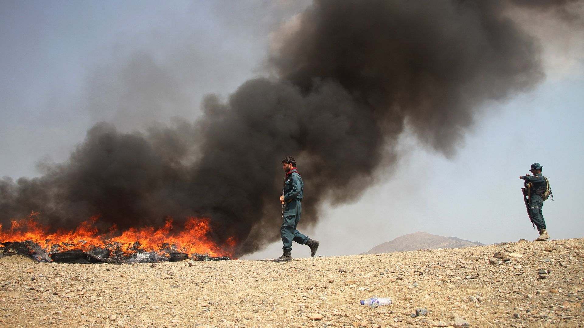 Photo of a person walking past a large fire in a desert