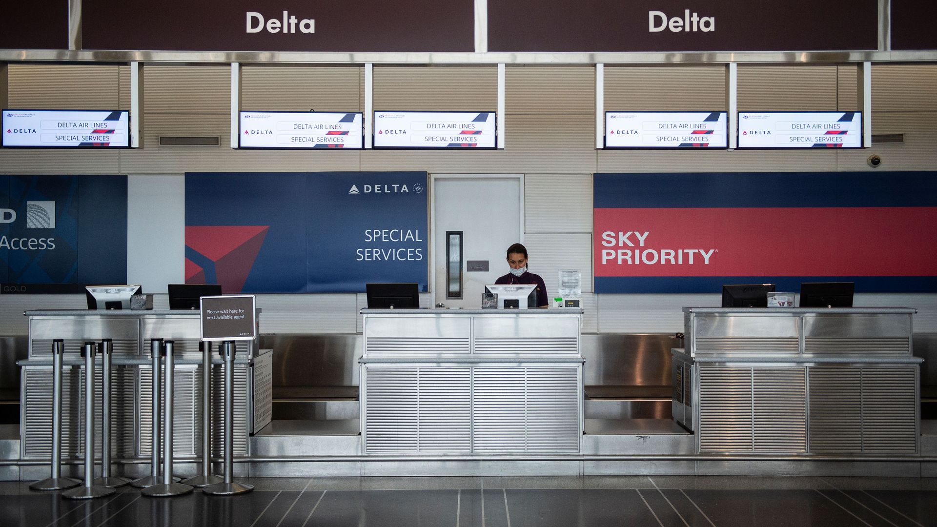 Picture of a Delta employee behind a counter wearing a mask