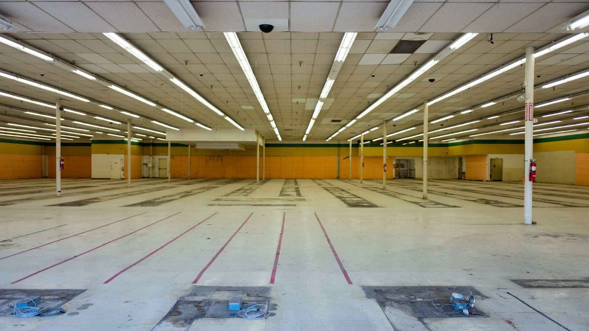 This image shows the inside of an empty and abandoned retail store with the fluorescent lights on.