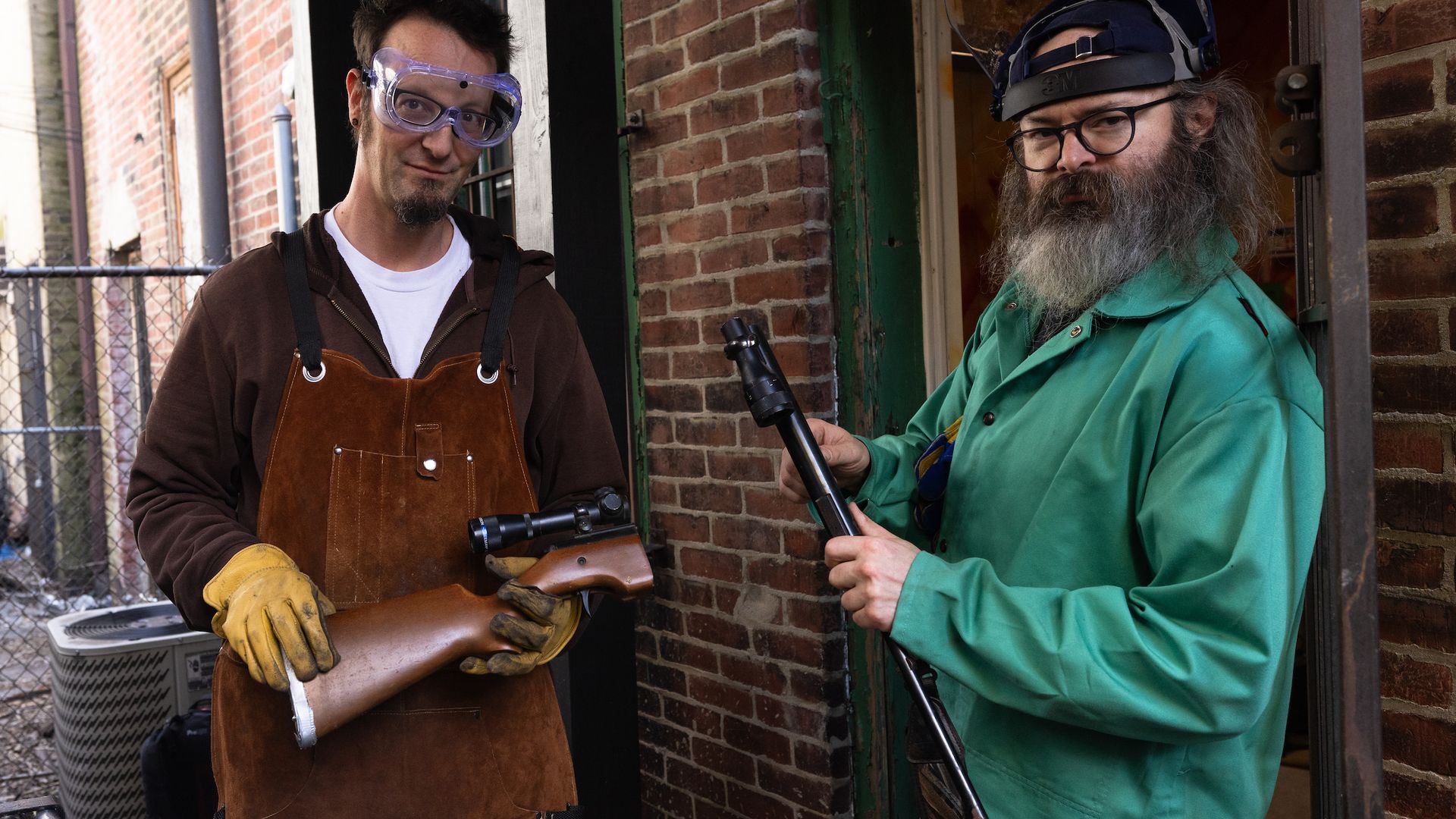 Philly artists Shane Claiborne, left, and Jacob "Chris" Hammes, holding chopped-up parts of a rifle.
