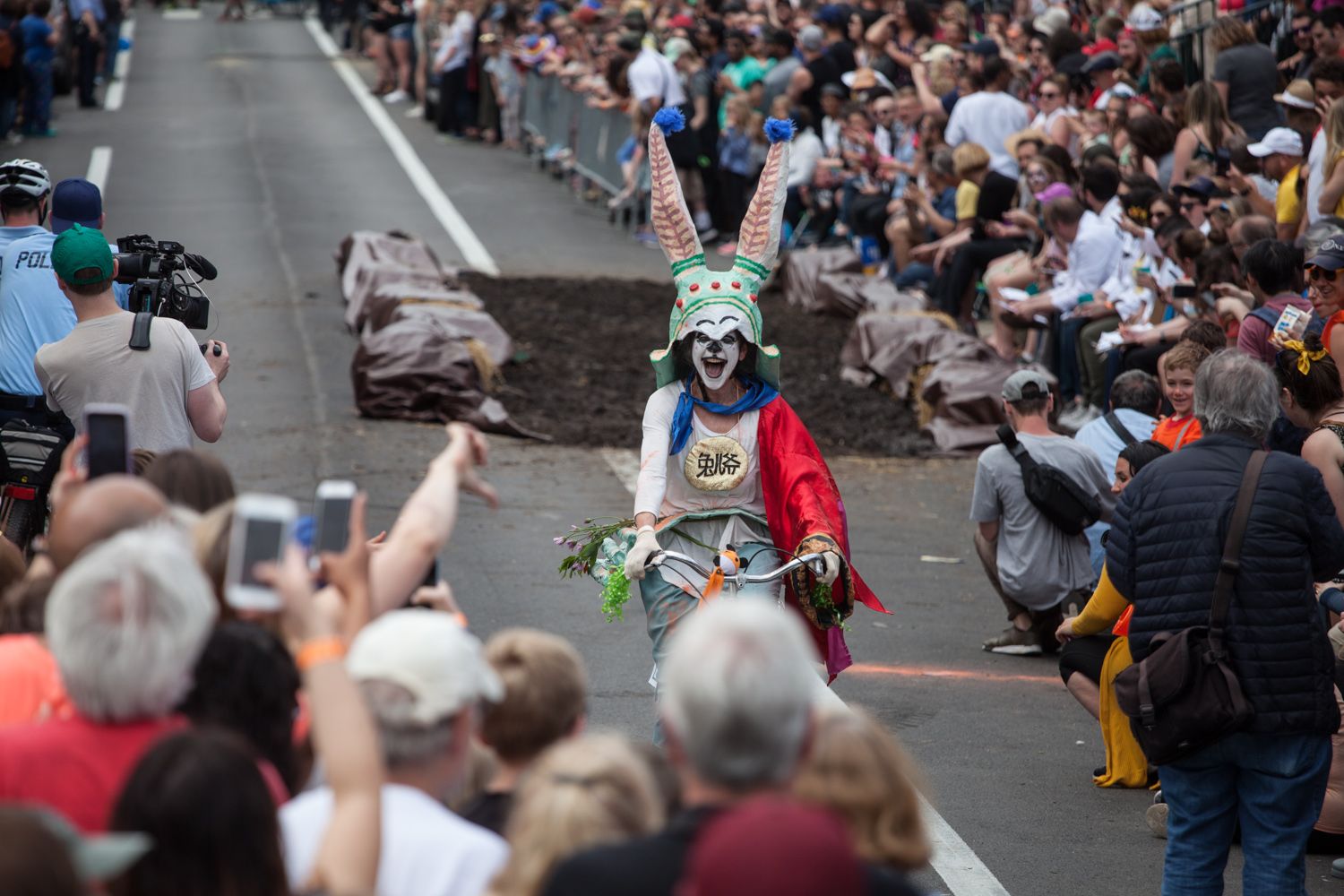 A derby contestant dressed in a rabbit costume rides past a mud pit