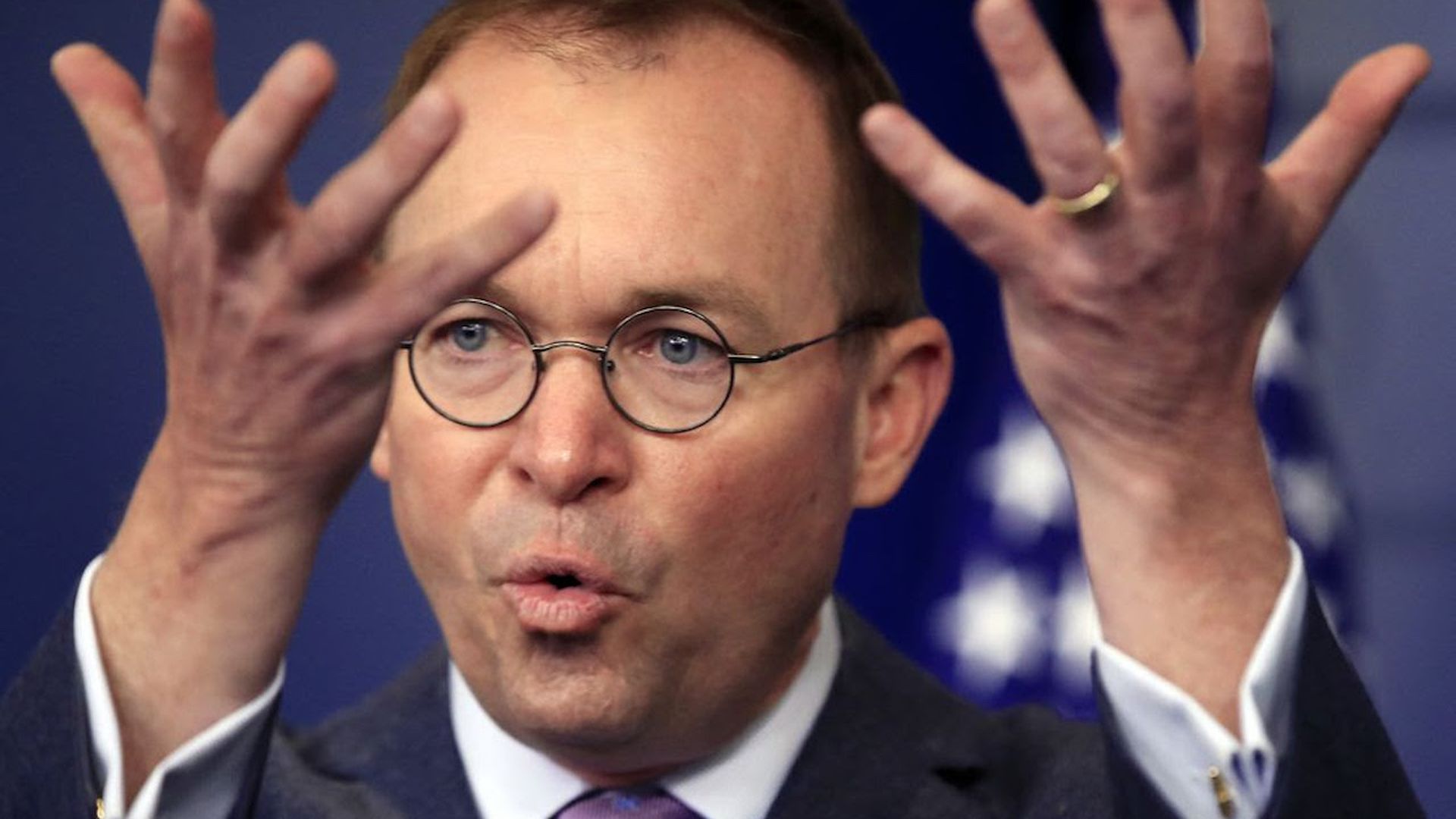 Mick Mulvaney with his hands raised in front of his face.