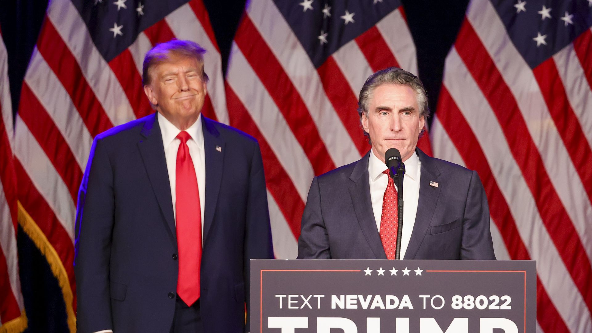 Former US President Donald Trump, left, listens as Doug Burgum, governor of North Dakota, speaks during a Nevada Republican caucus night watch party