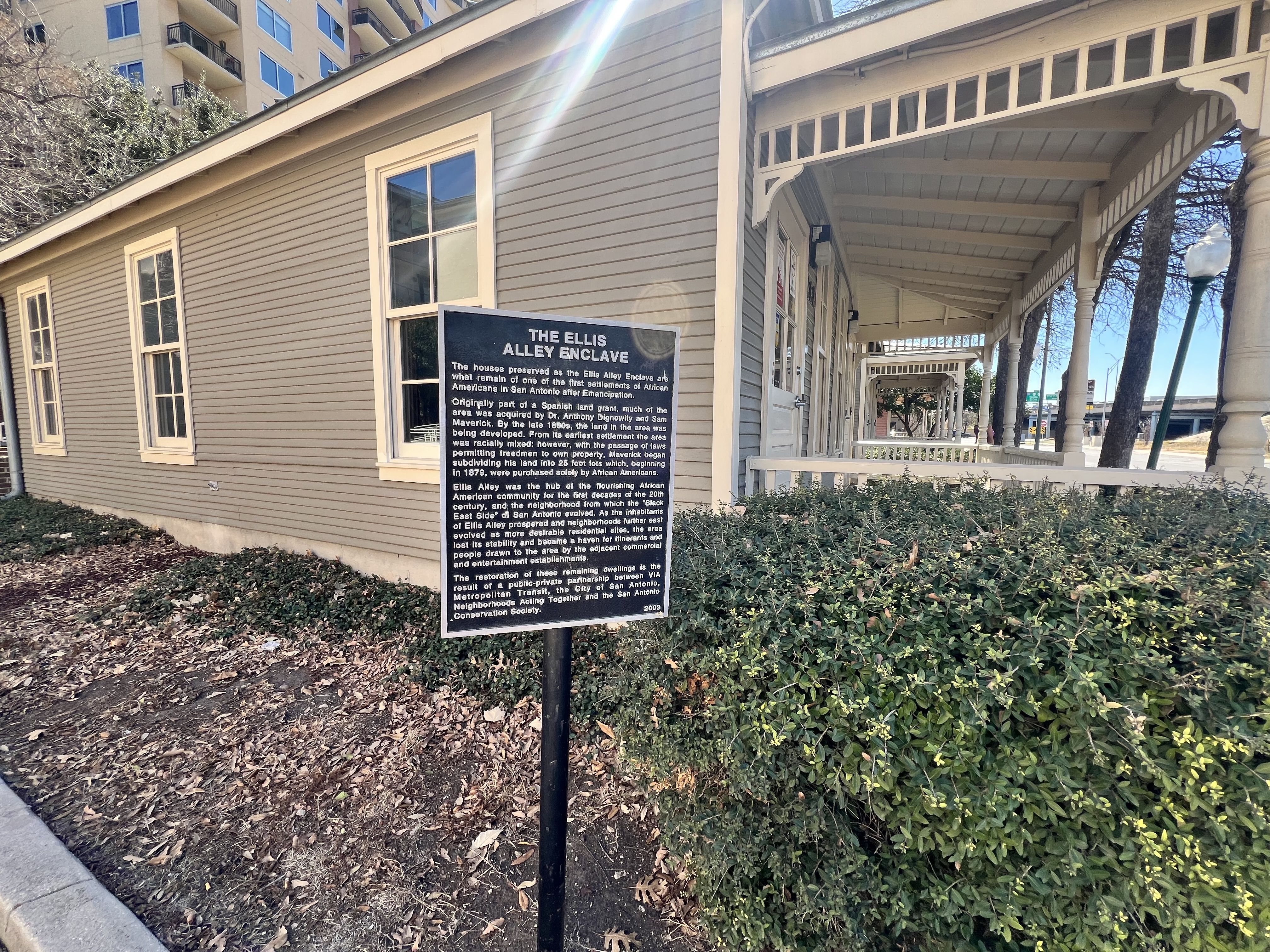 Historic wooden building with beige siding and informational sign