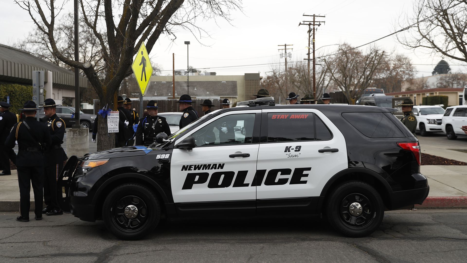In this image, a police SUV is parked on the curb of a parking lot. 