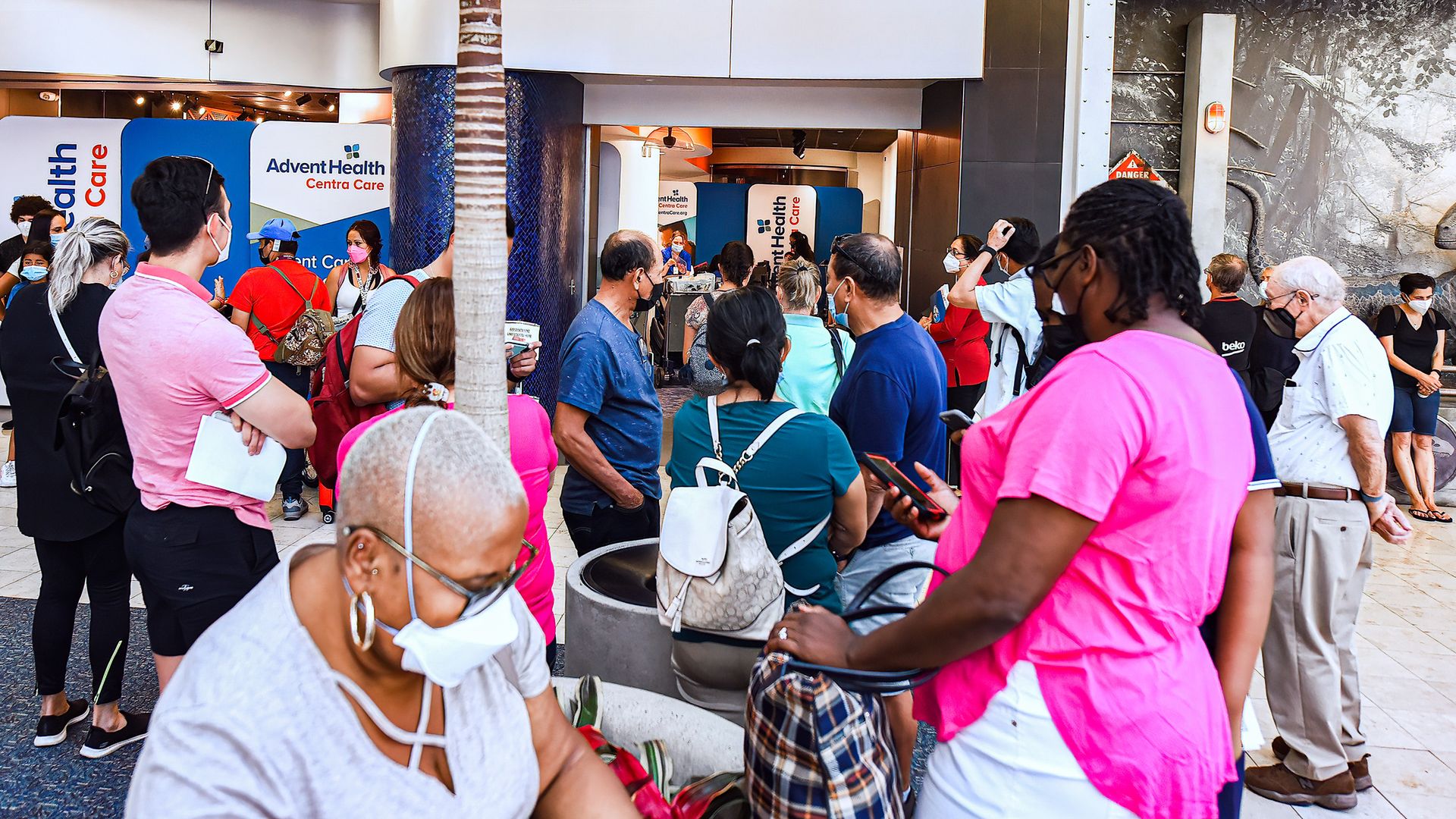 People wearing facemasks line up at a COVID-19 testing site at Orlando International Airport.