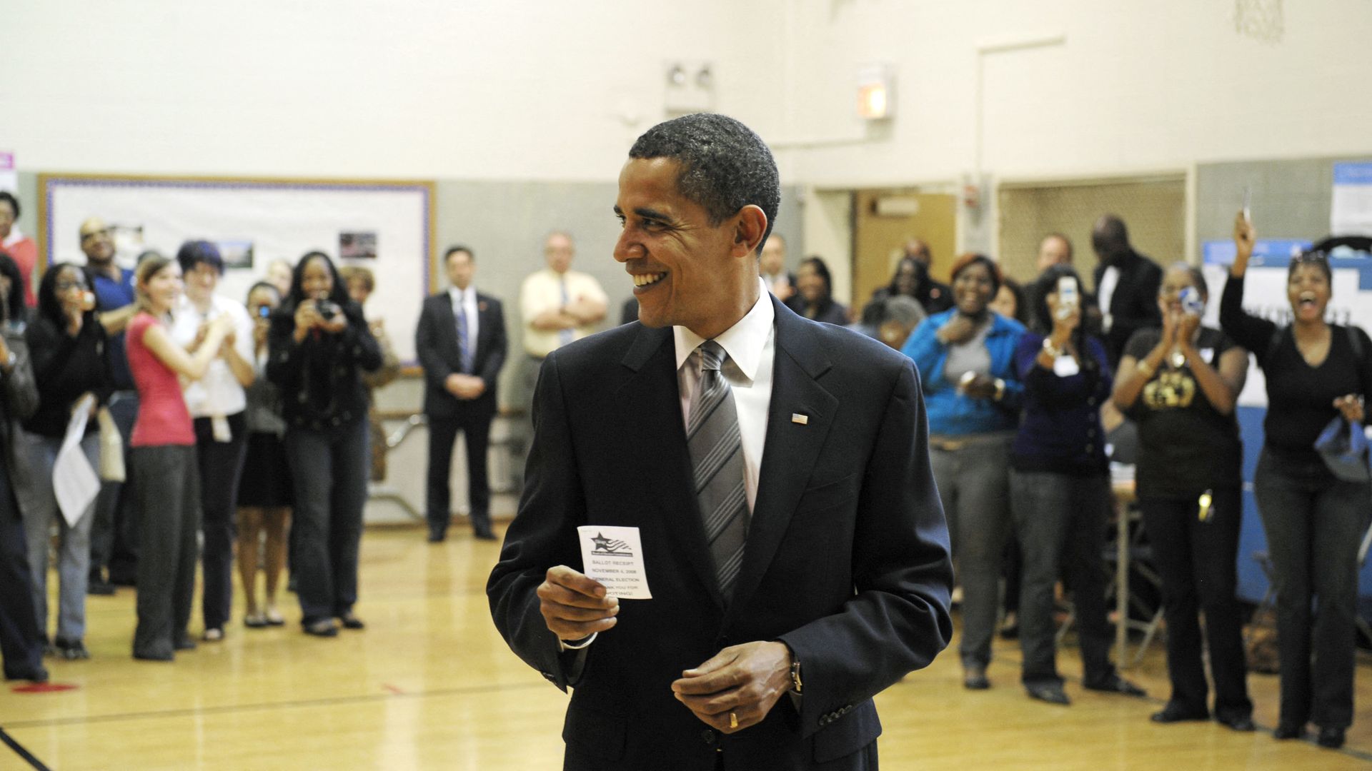 Photo of a man with a ballot receipt in his hand while voting in a school gymnasium 