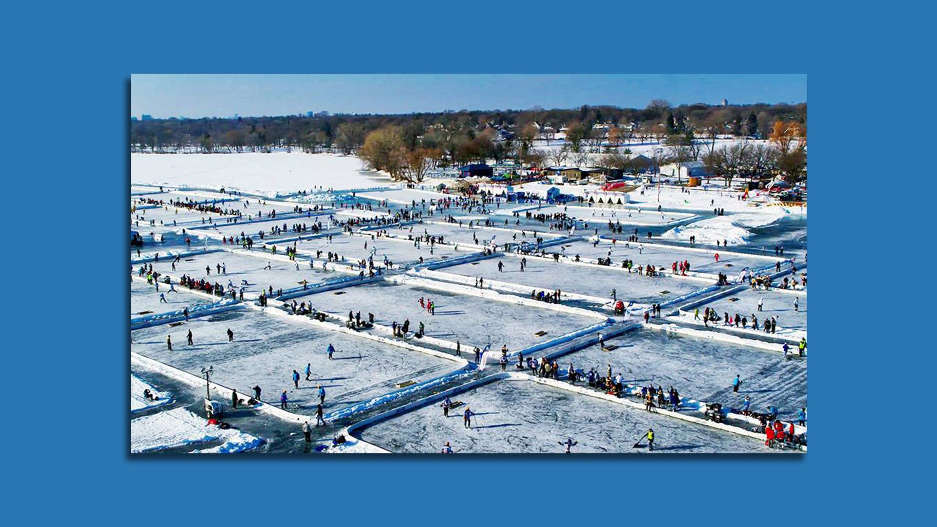 A large frozen lake divided into several ice rinks with groups of people gathered.