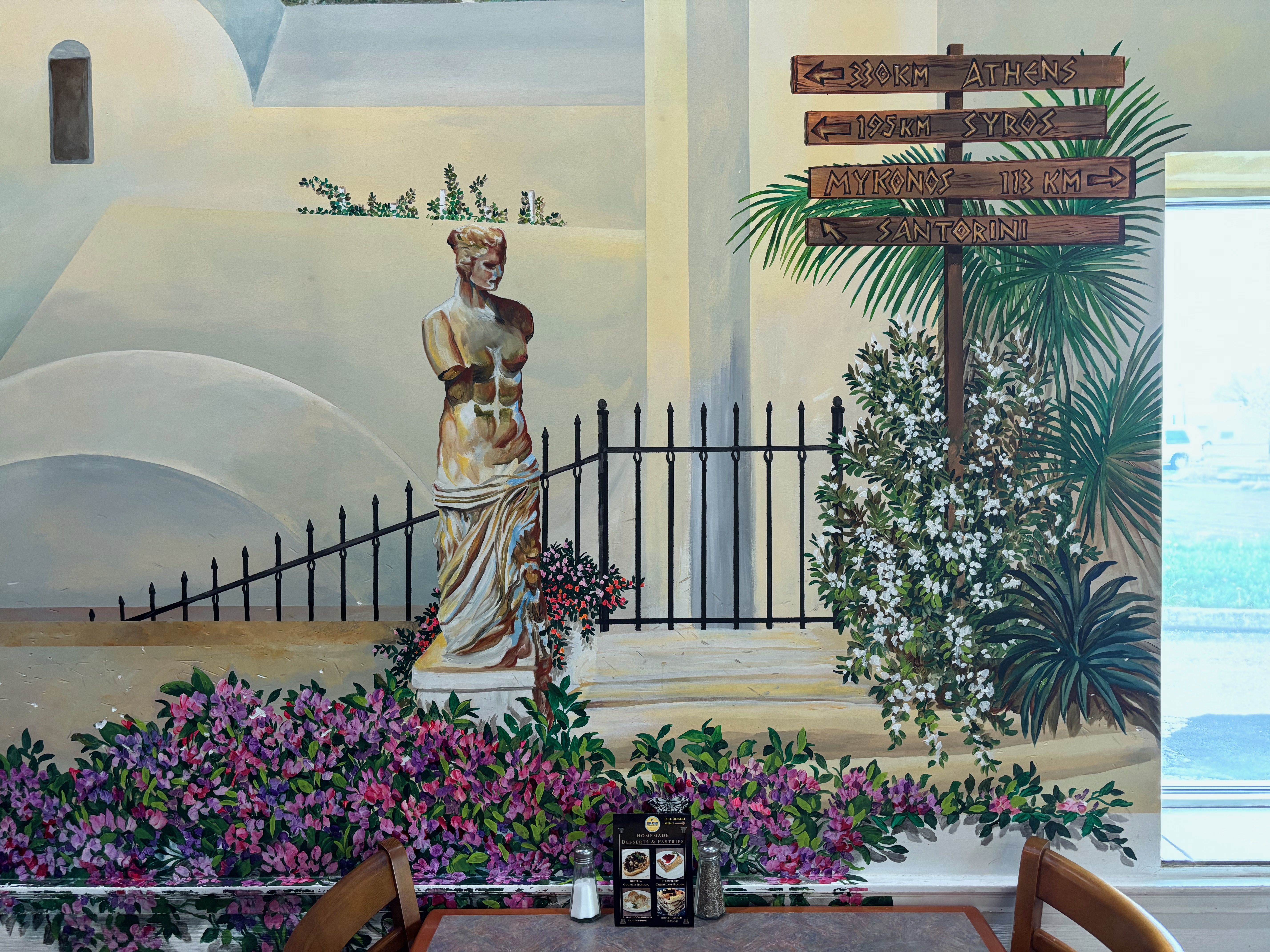 A wall mural of flowers and a Greek statue inside King Gyros