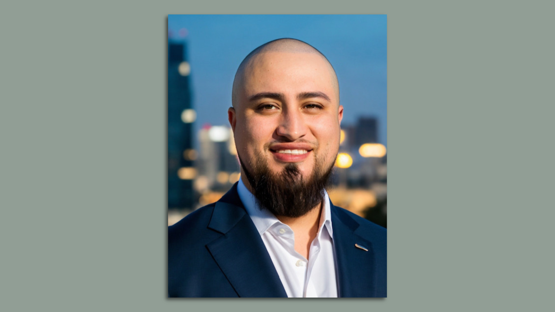 Photo of Jose Morales in a navy suit and white collared shirt smiling at the camera