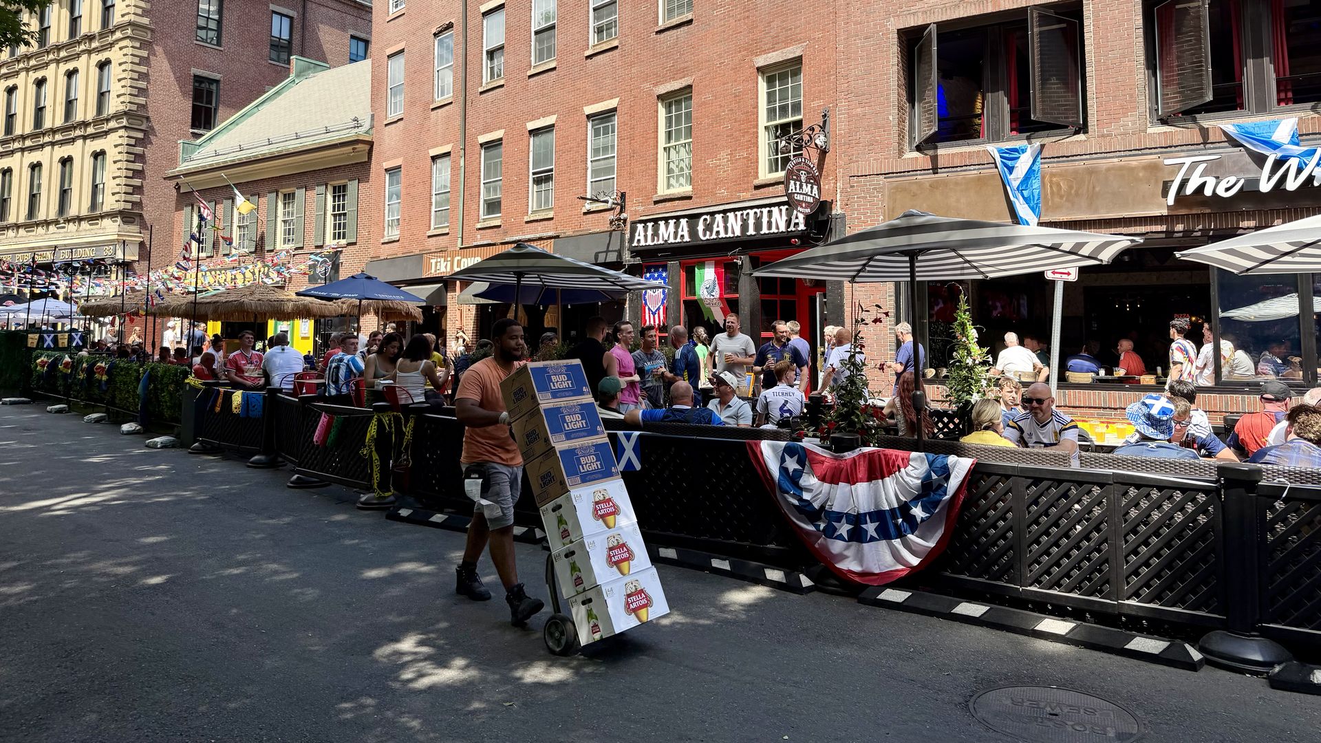 A delivery driver rolls cases of beer into a bar on Union Street in Boston as Scotland fans and other World Cup fans watch matches and drink.