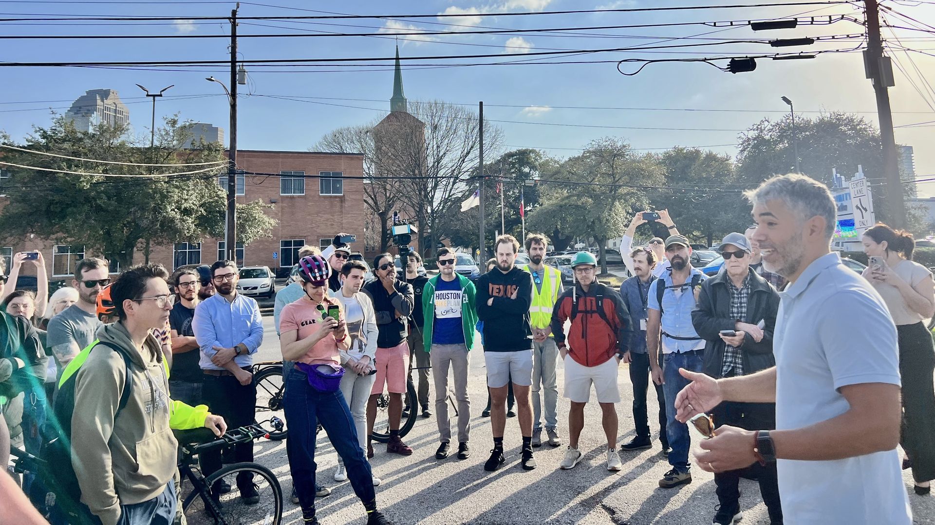 Photo of a people in a crowd, with one man in a blue polo speaking