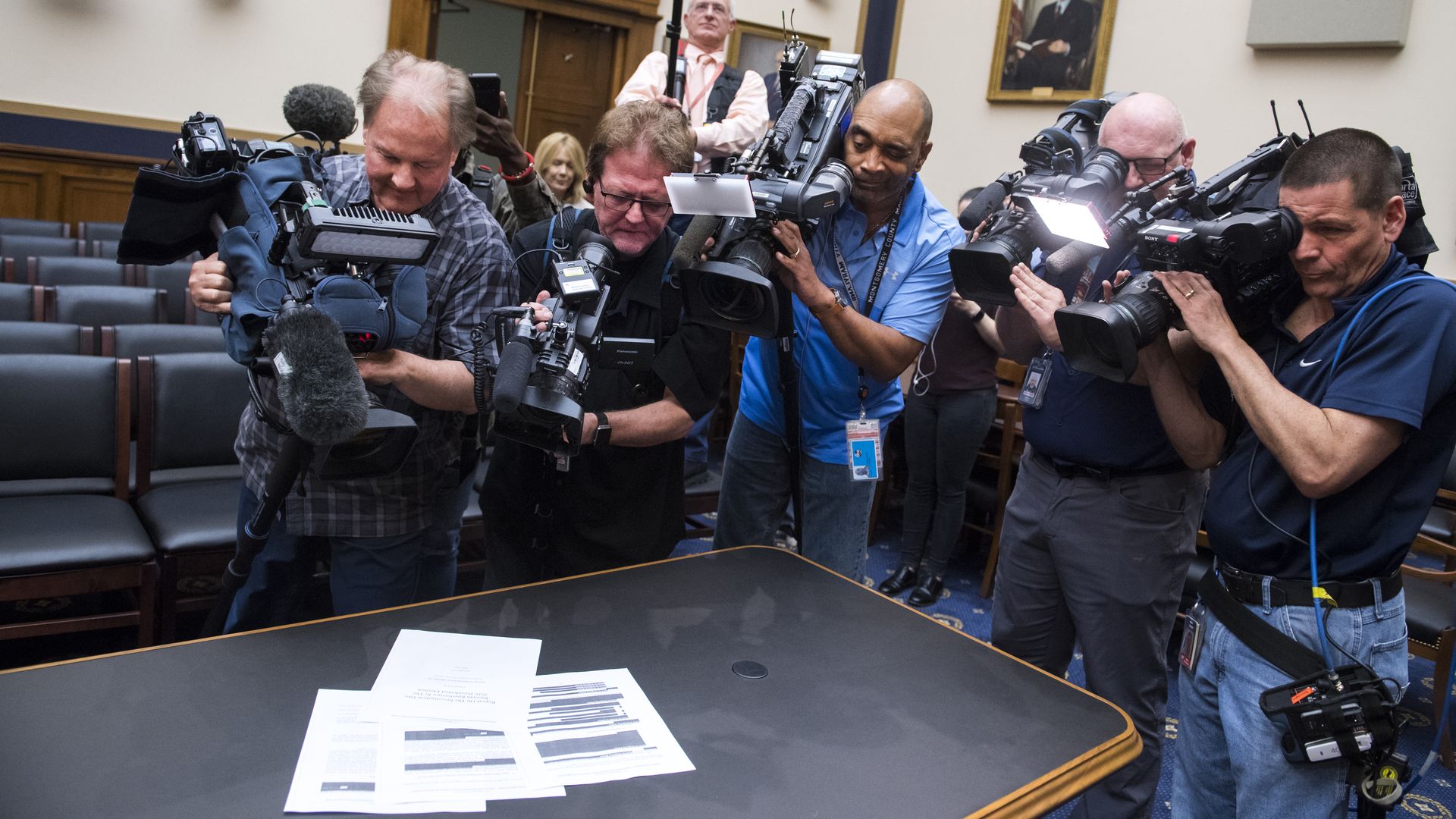 In this image, a crowd of reporters with cameras take pictures of papers in the Mueller report as it sits on a table. 