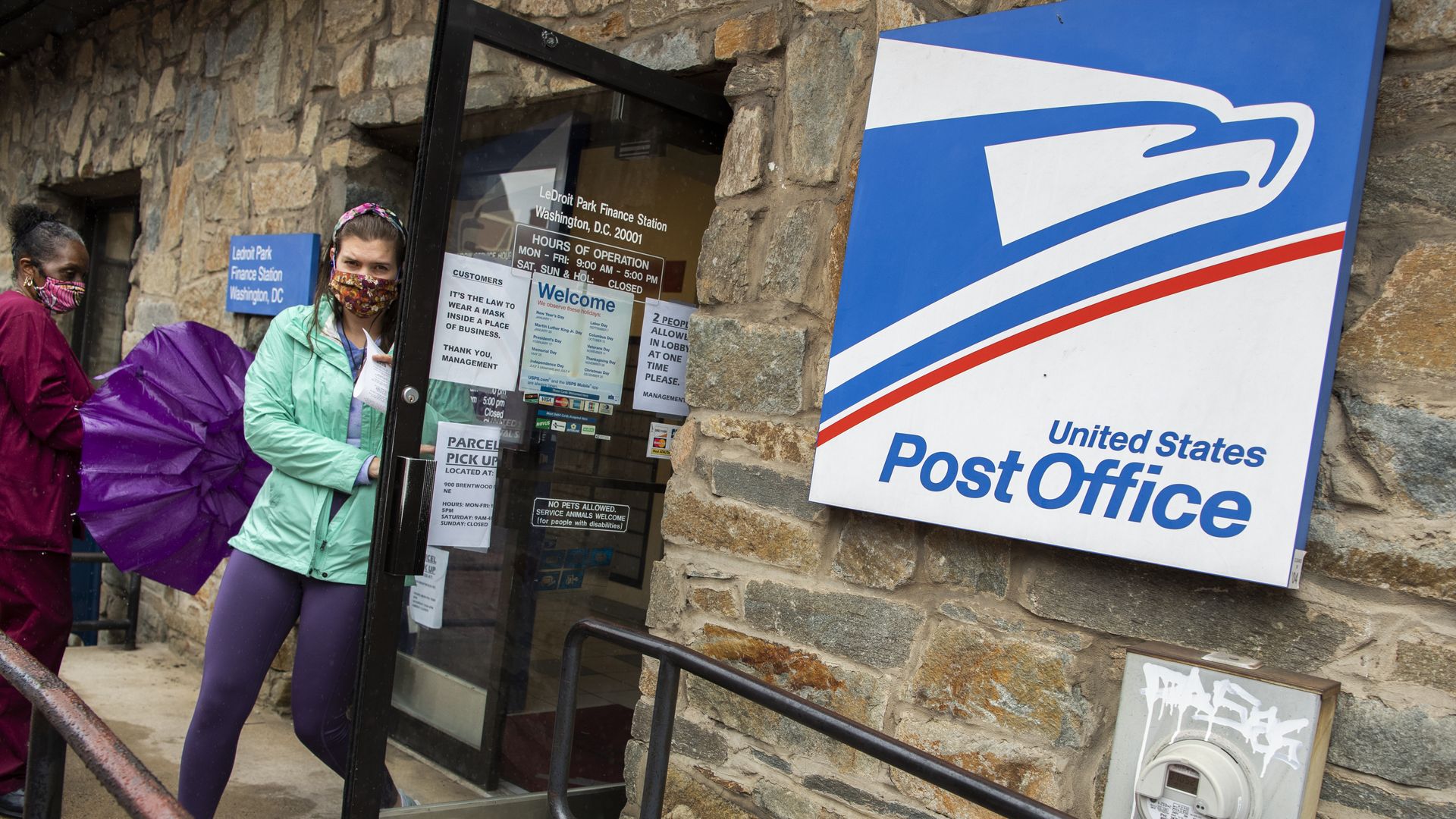 USPS sign next to a woman opening a post office door 