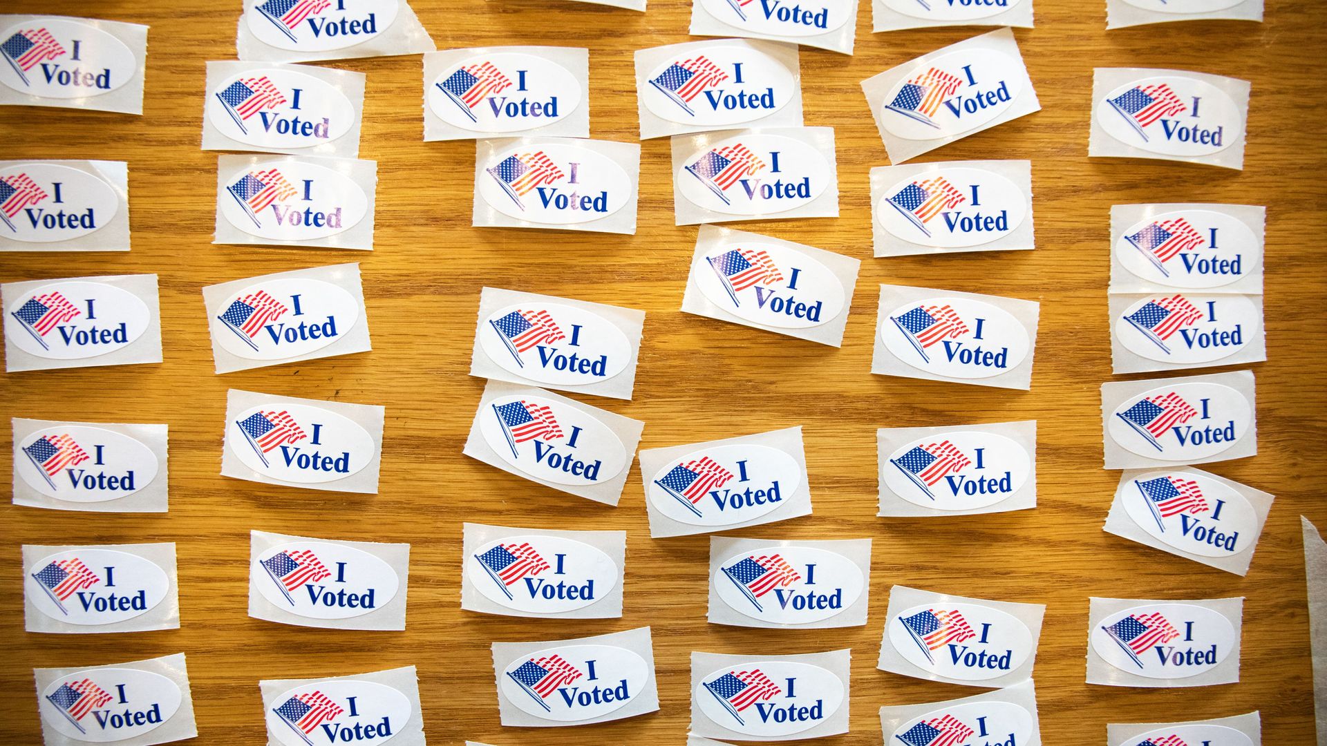 In this image, rows of "I voted" stickers are laid out on a table.