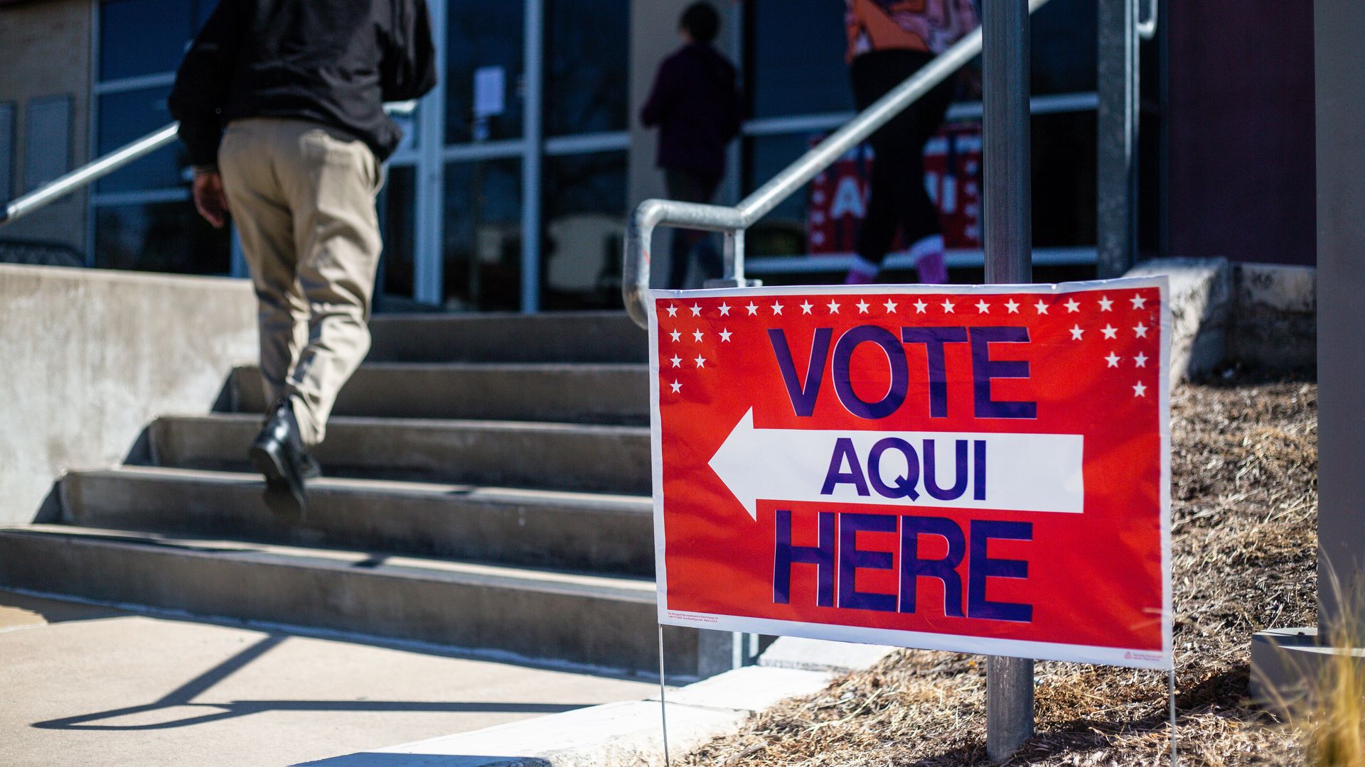 Photo of a red sign that says "Vote aqui here" next to a building