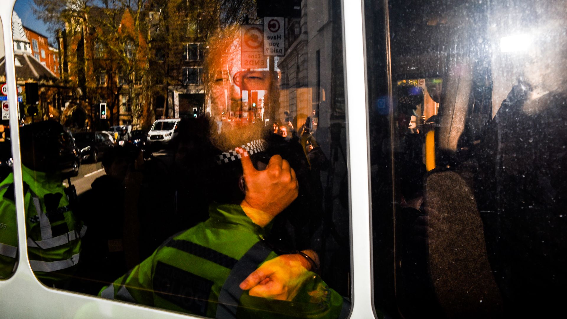 In this image, Assange gives a thumbs up to reporters from inside a vehicle. 