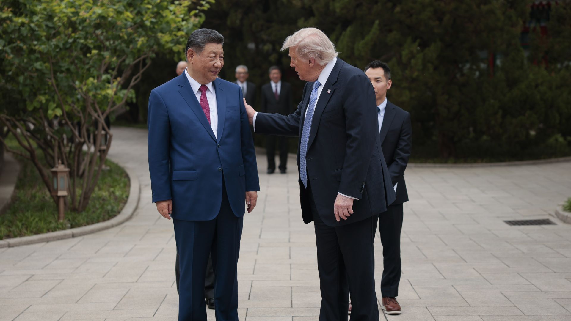 Xi Jinping and Donald Trump stand side by side in Beijing with Trump's right hand on Xi's left shoulder
