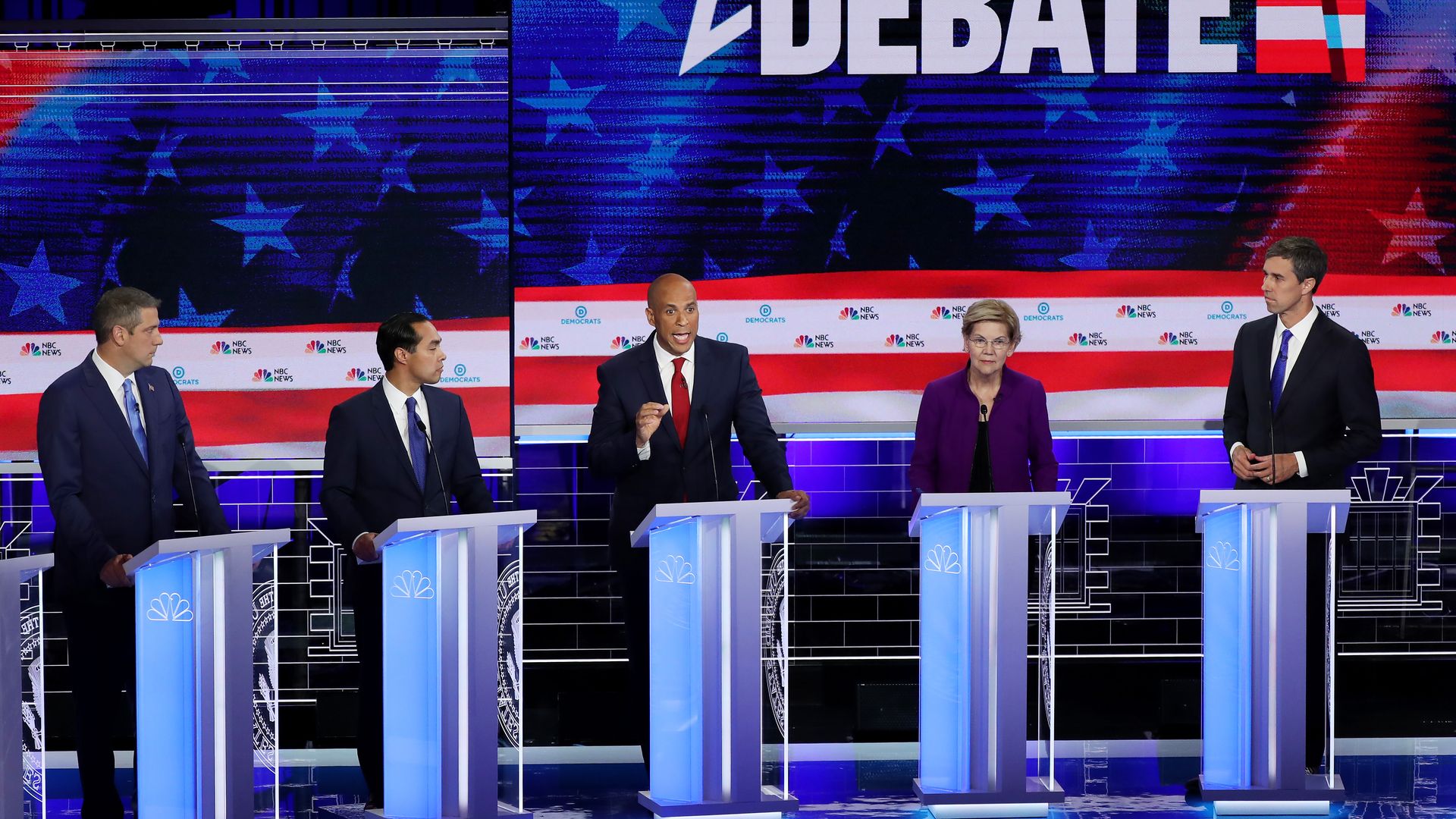 The debate stage with candidates at their podiums.