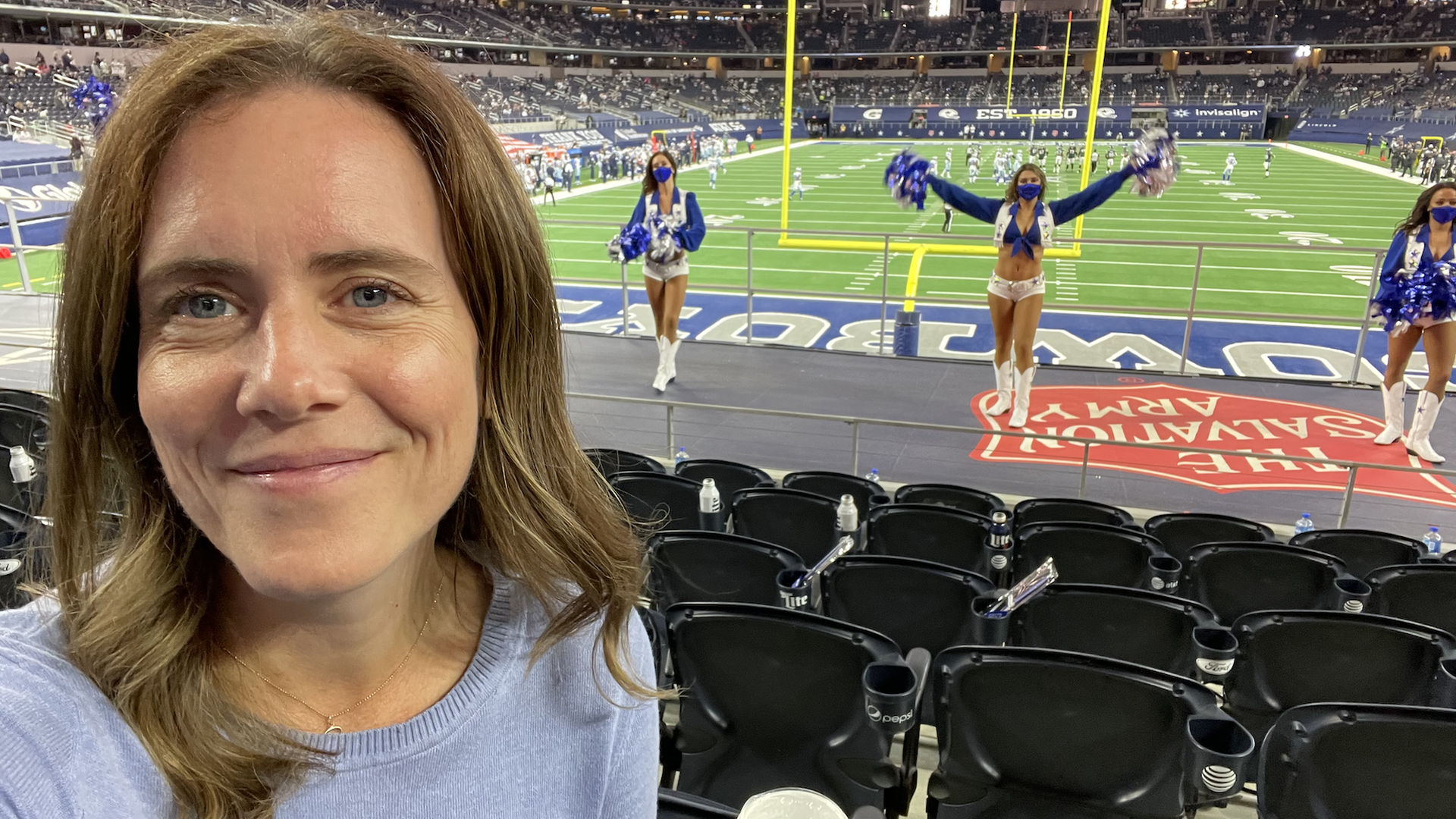A woman in front of some Dallas Cowboys cheerleaders