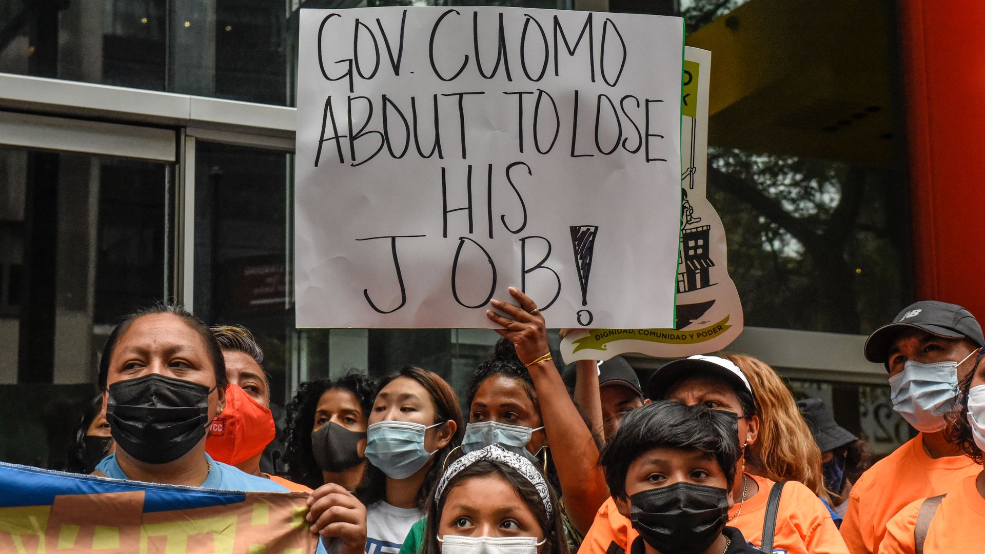 Protestors are seen holding up a sign urging New York Gov. Mario Cuomo to resign.