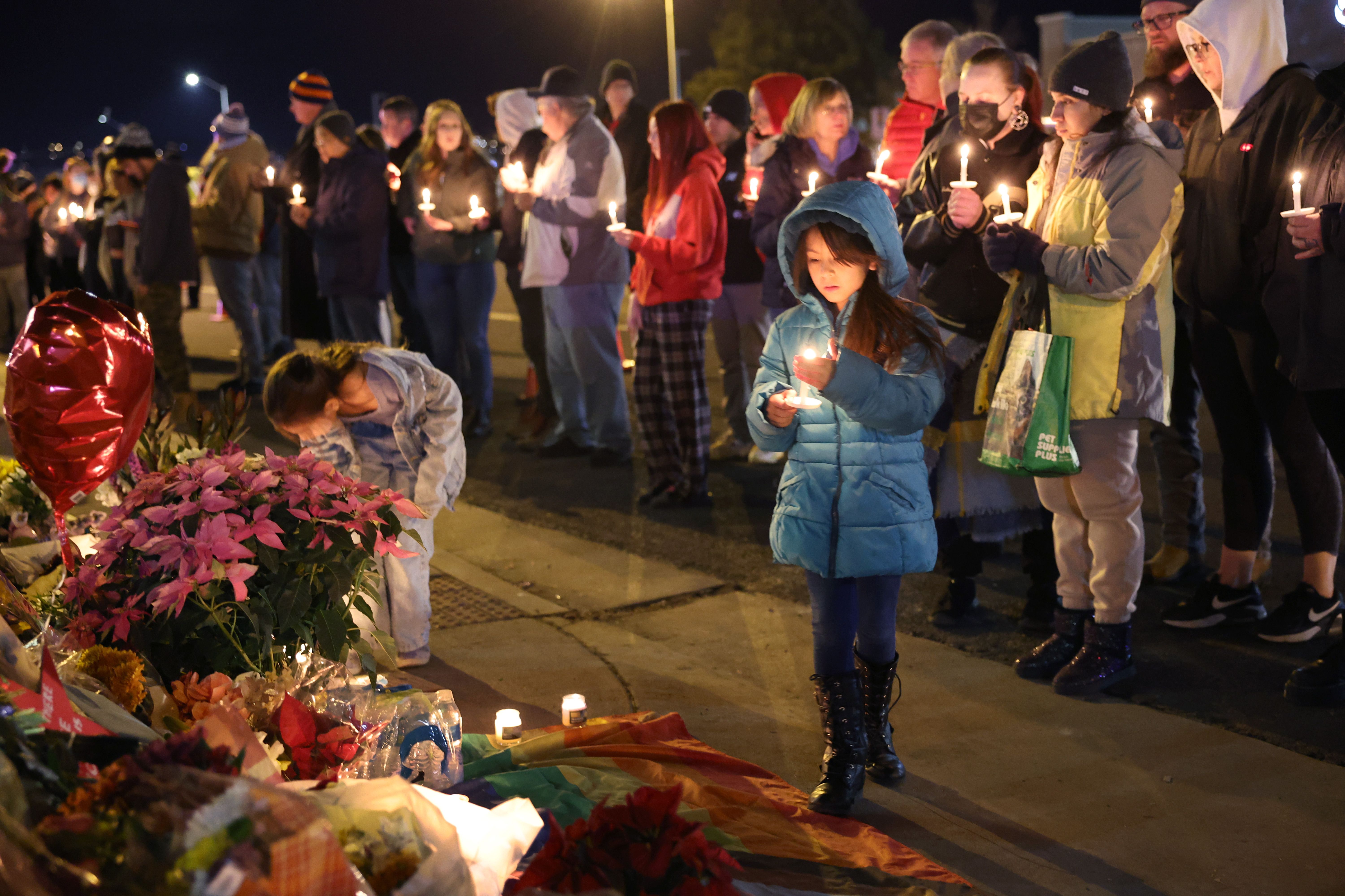 People hold a vigil at a makeshift memorial near the Club Q nightclub on November 20, 2022 in Colgs, Colorado. 