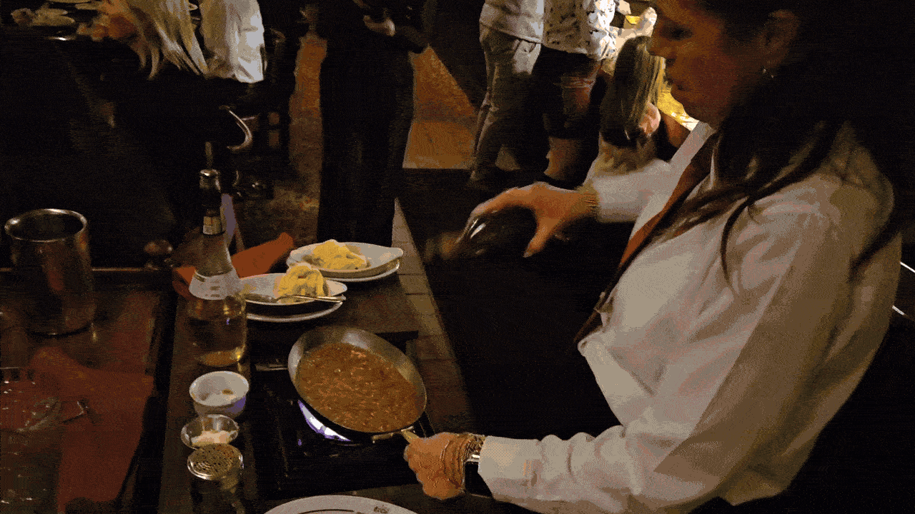 A server prepares bananas foster at Sperry's with flames towering over a saucepan.
