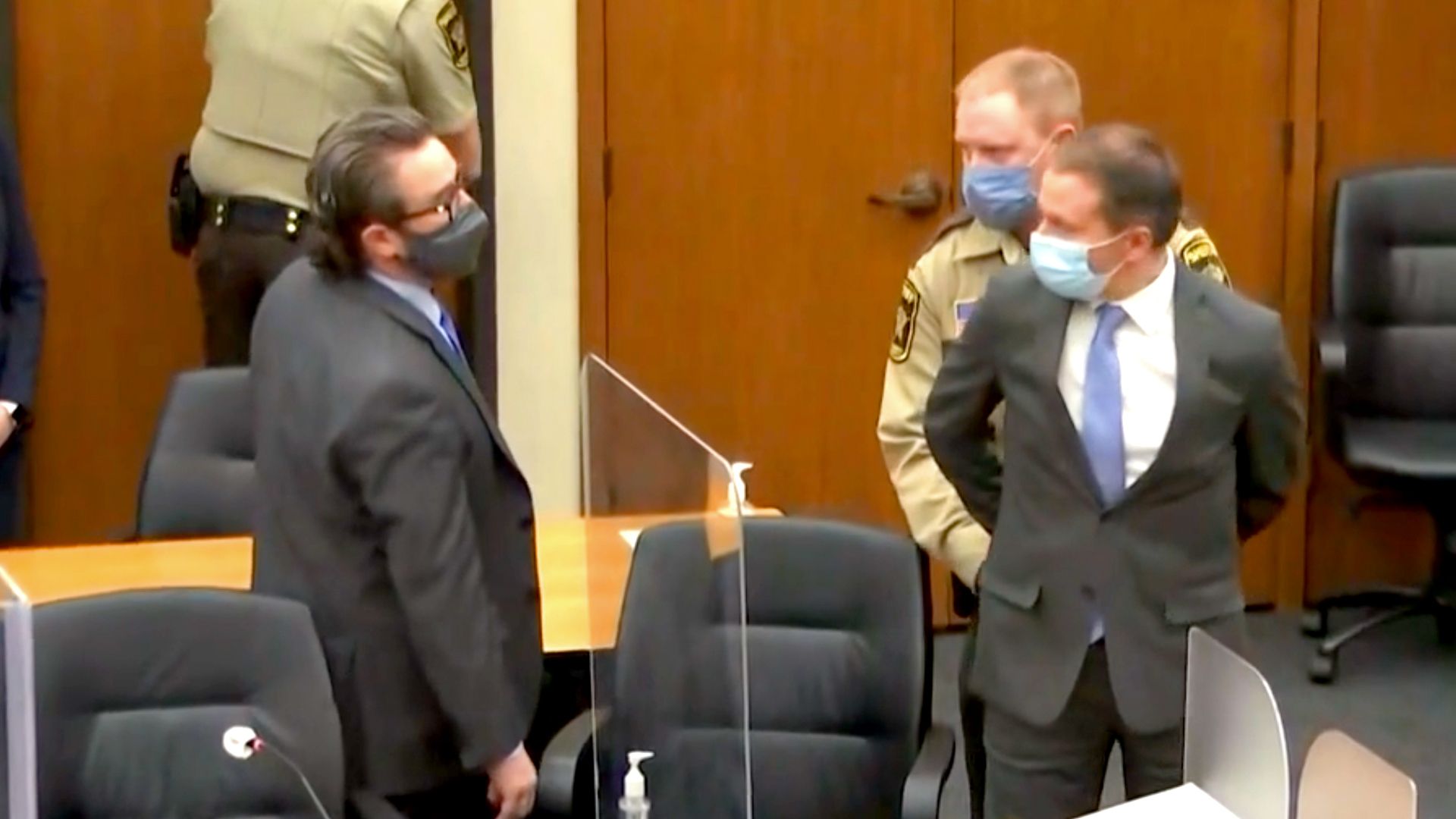 Derek Chauvin is handcuffed while looking at his attorney 