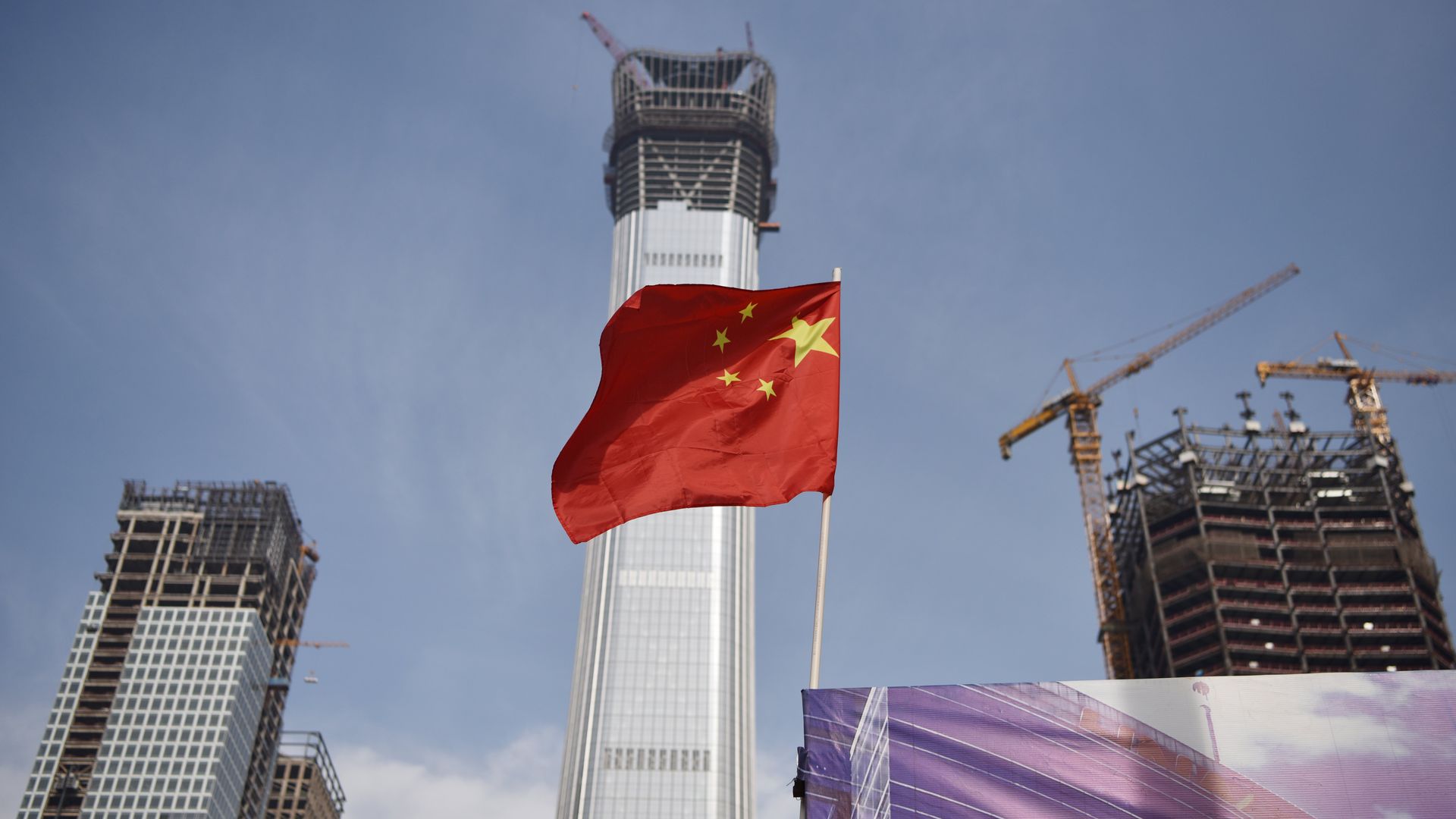 A Chinese national flag flies at the construction site for new buildings in Beijing's central business district 